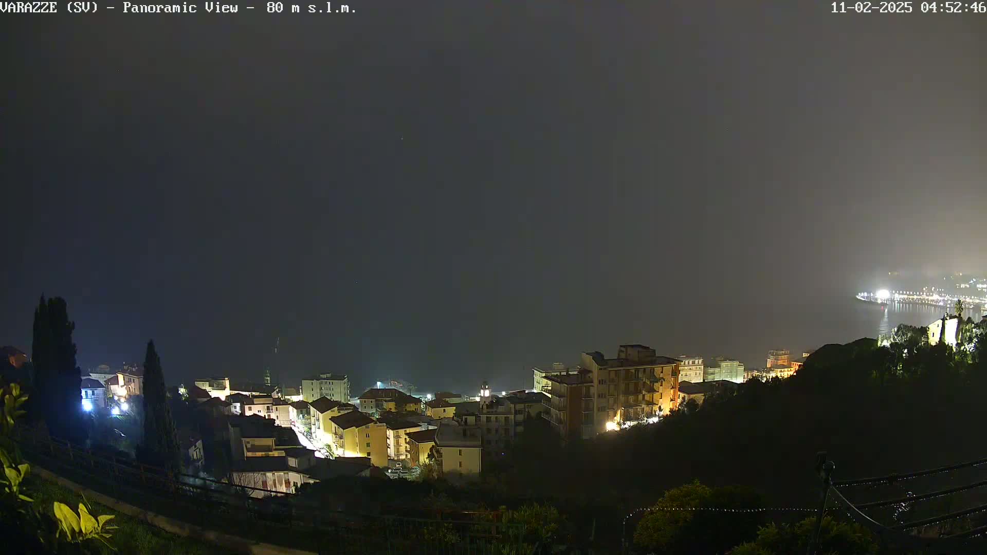 A nighttime, foggy view overlooking a coastal town with its buildings illuminated.