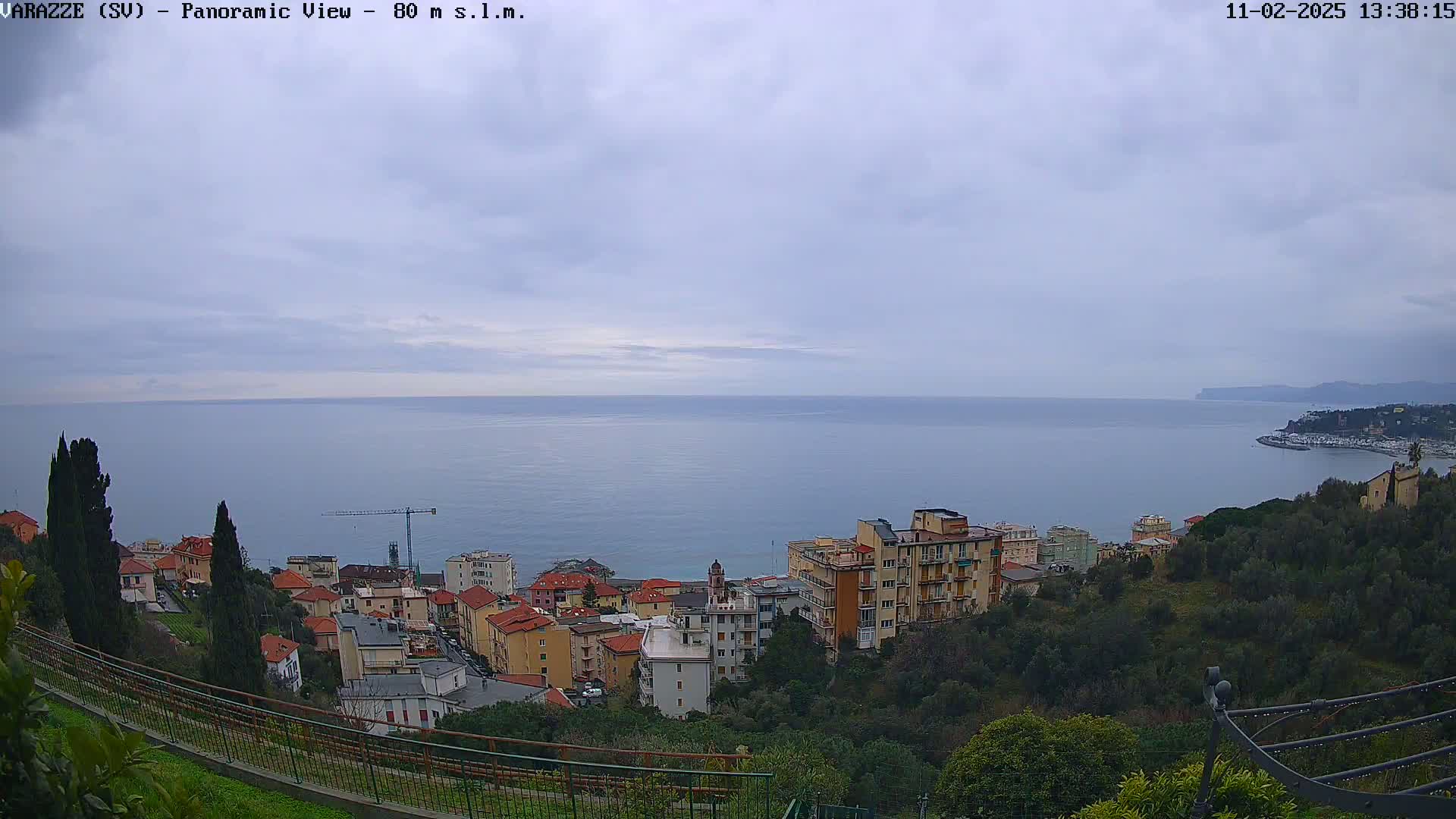 A coastal town overlooks a calm sea under a cloudy sky.