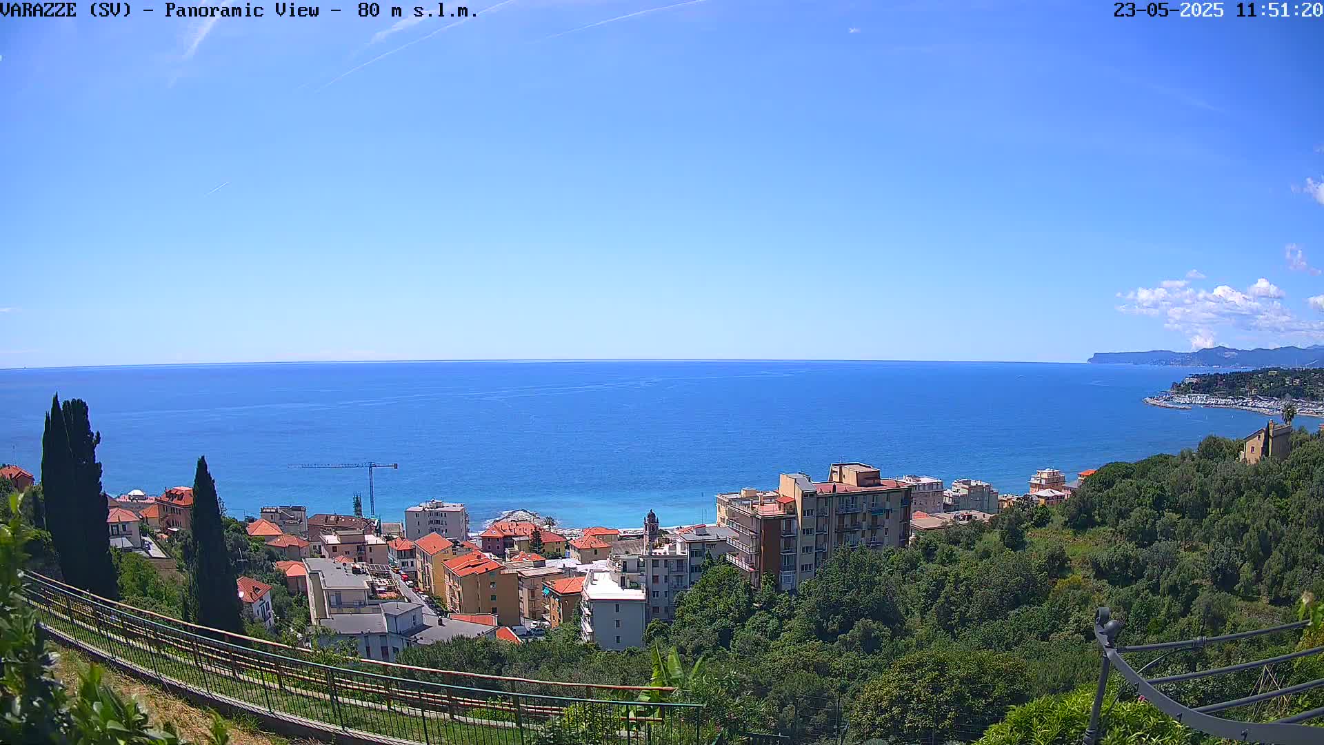 A panoramic view of a coastal town on a clear, sunny day, overlooking a calm blue sea.