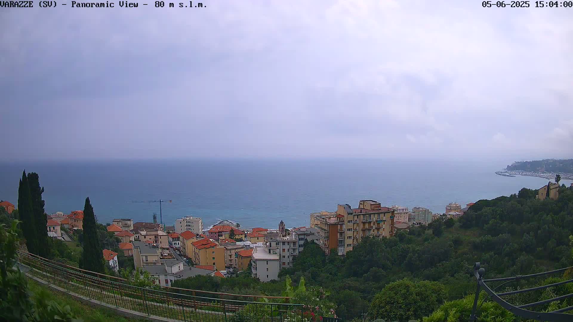 A coastal town with low-rise buildings overlooks a calm sea under a cloudy sky.