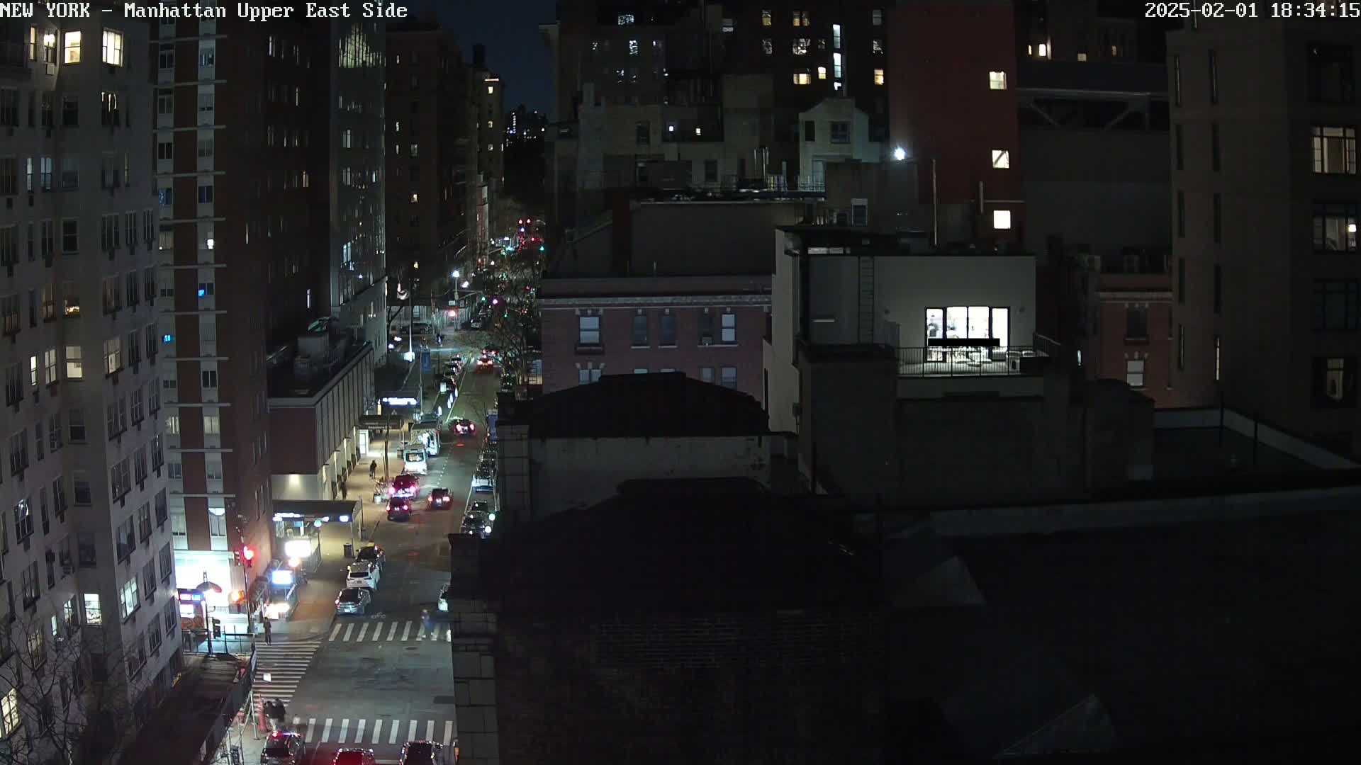A nighttime, high-angle view of a city street with traffic and several lit-up buildings.