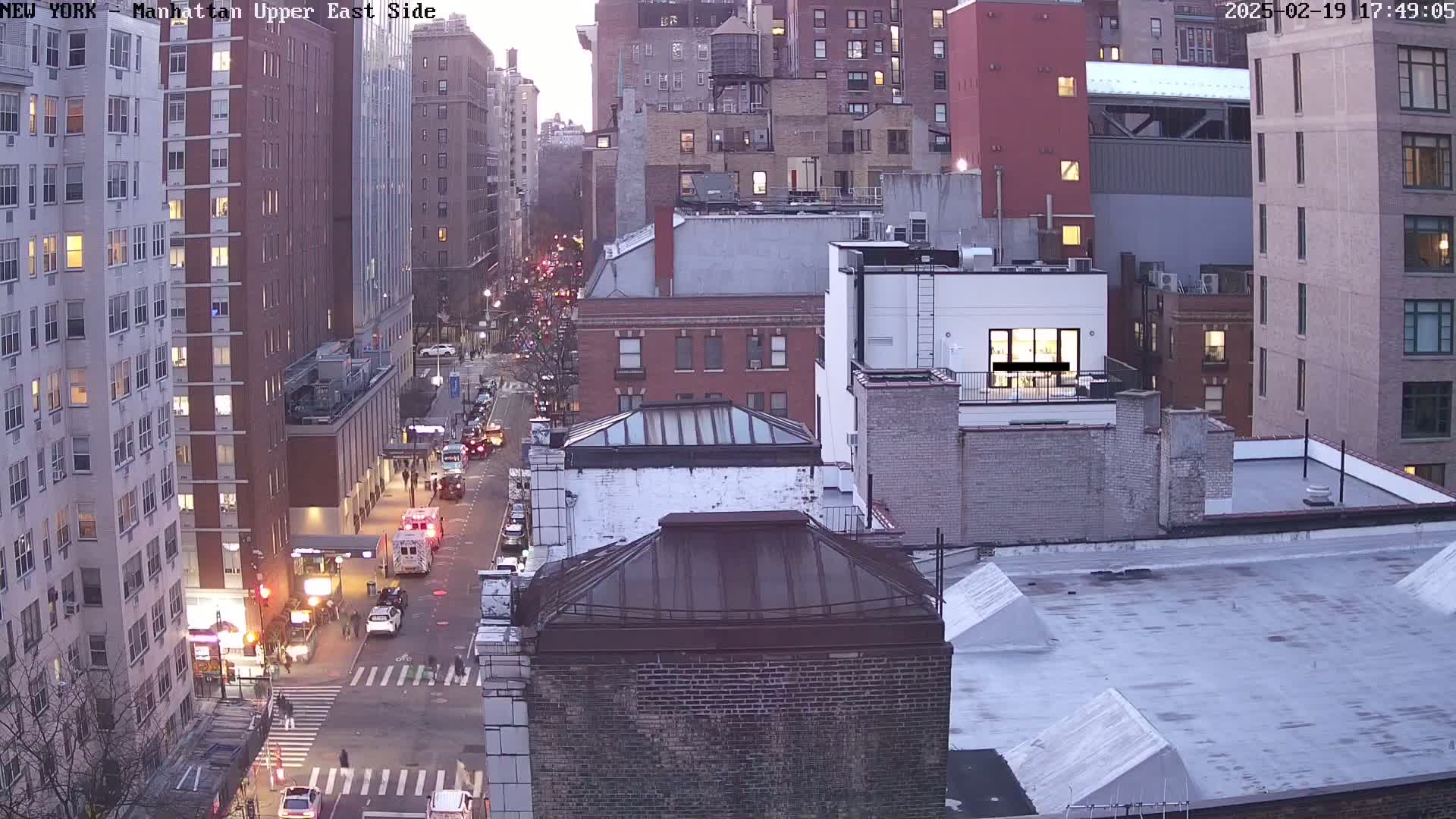 A high-angle, twilight view of a city street with traffic and several multi-story buildings.