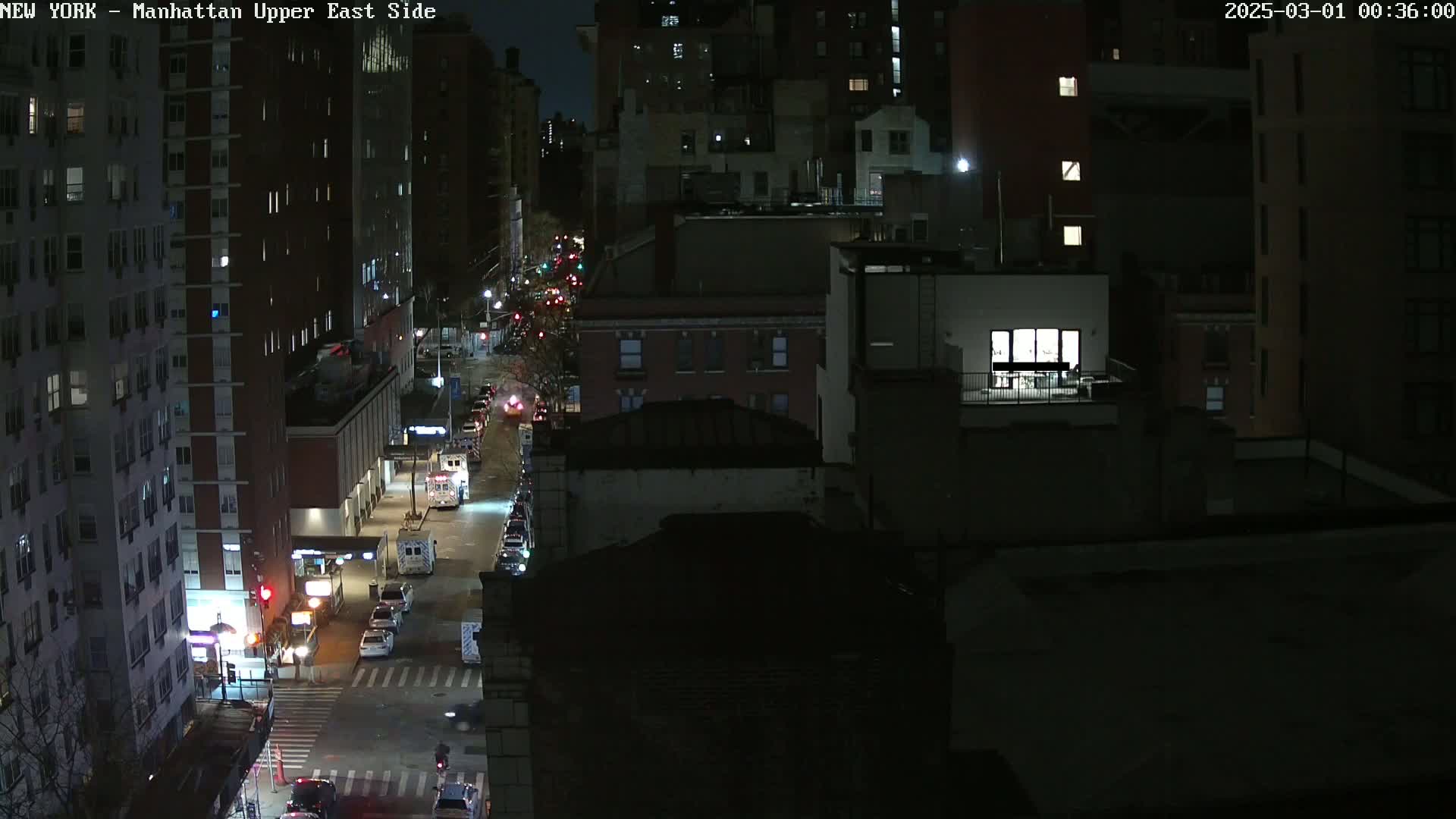 A nighttime, high-angle view of a city street with cars and buildings under dark conditions.