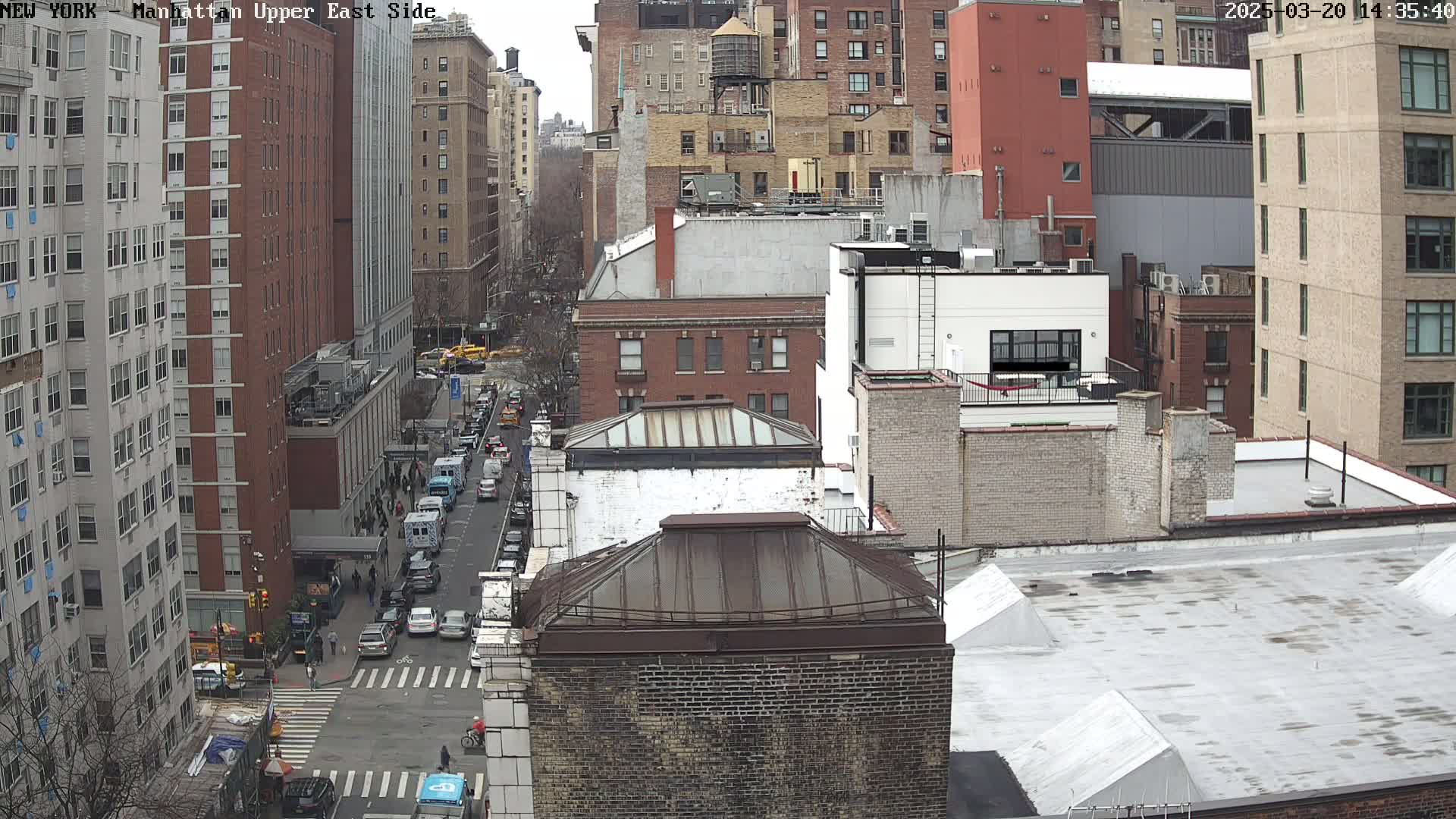 An aerial view of a city street scene showing several multi-story buildings on an overcast day.