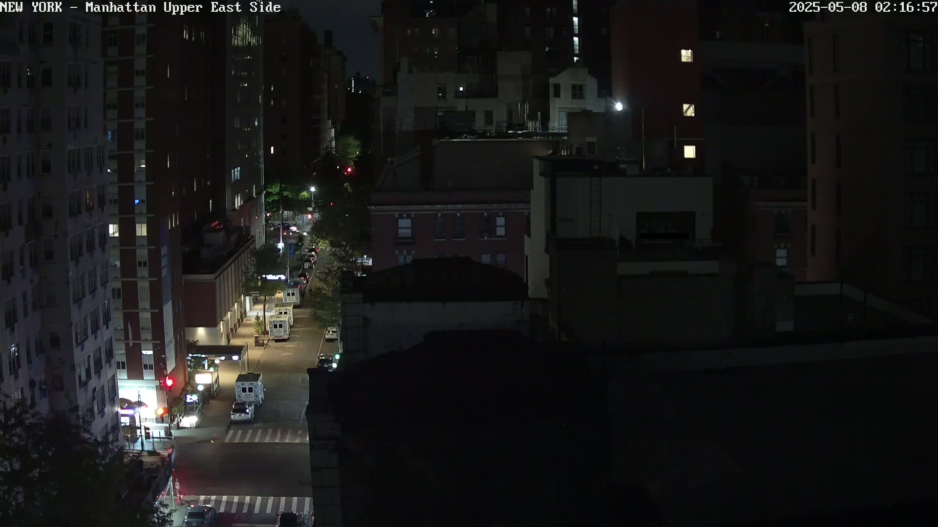 A nighttime, high-angle view of a city street with several vehicles and multi-story buildings.