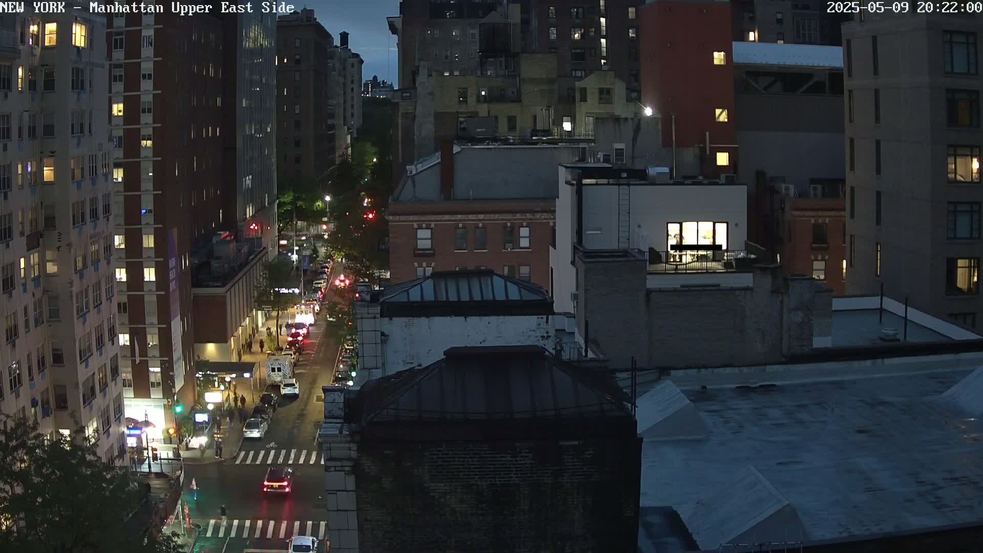 A nighttime aerial view of city streets and buildings, with a few cars on the road.