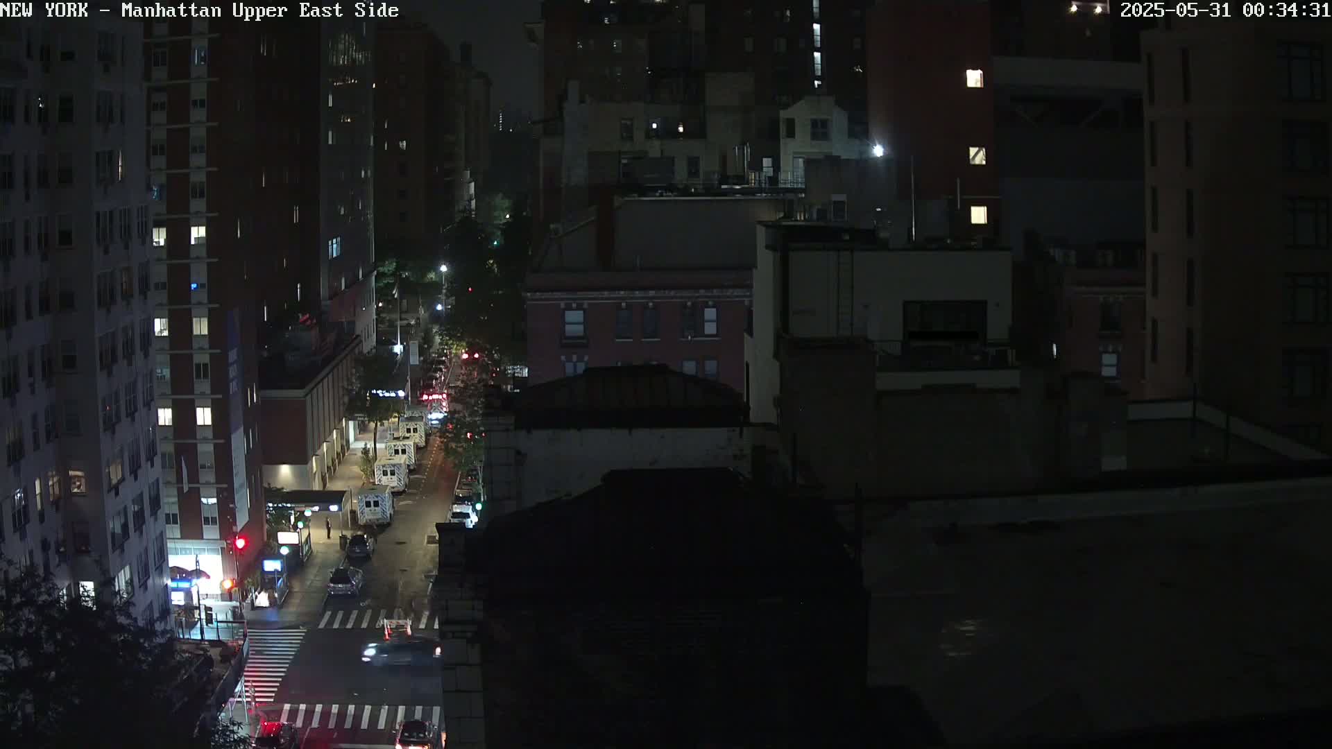 A nighttime, high-angle view of a city street with several cars and buildings, showing a clear sky.