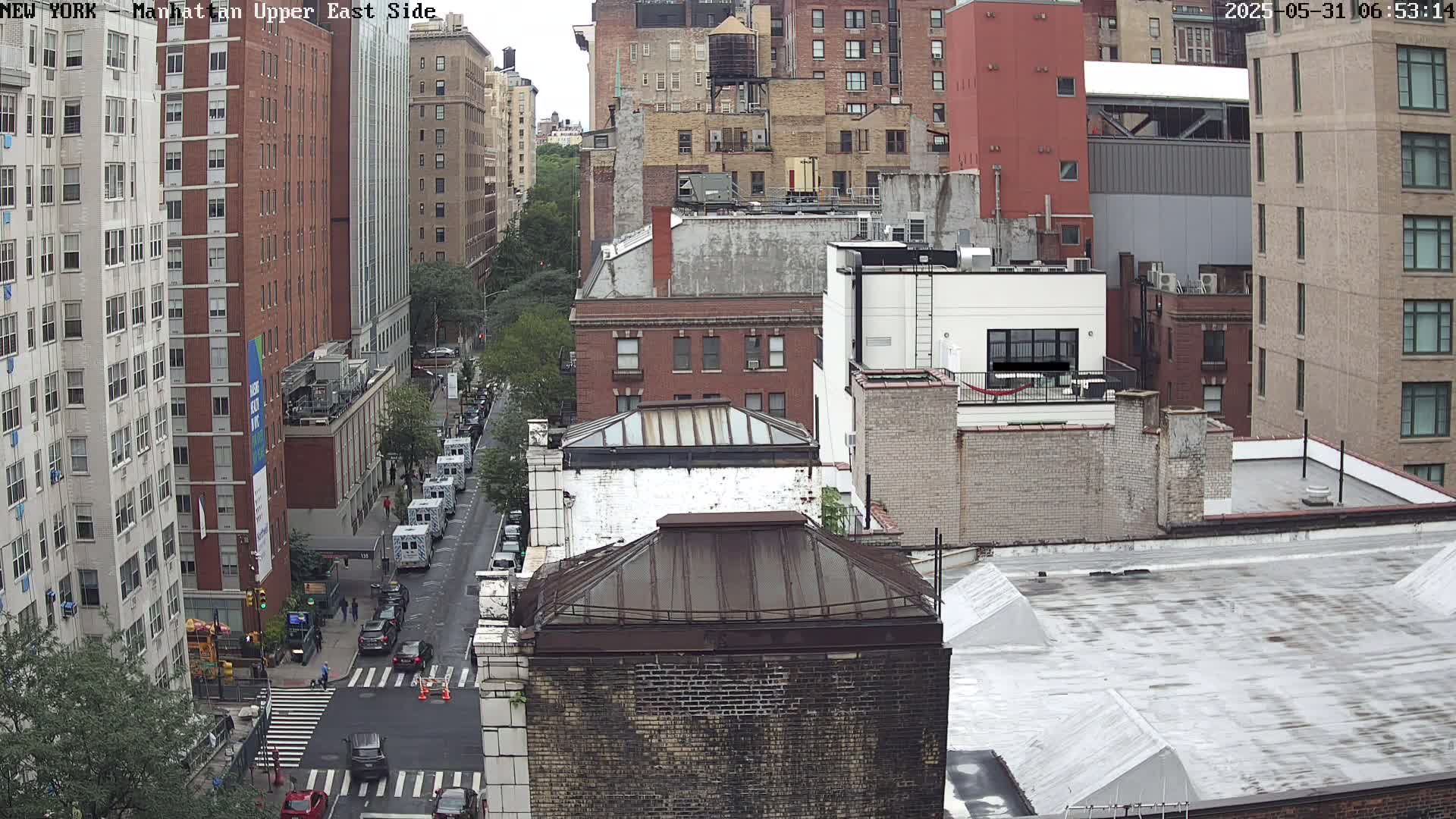 A high-angle view of a city street scene shows several multi-story brick buildings on a cloudy day.