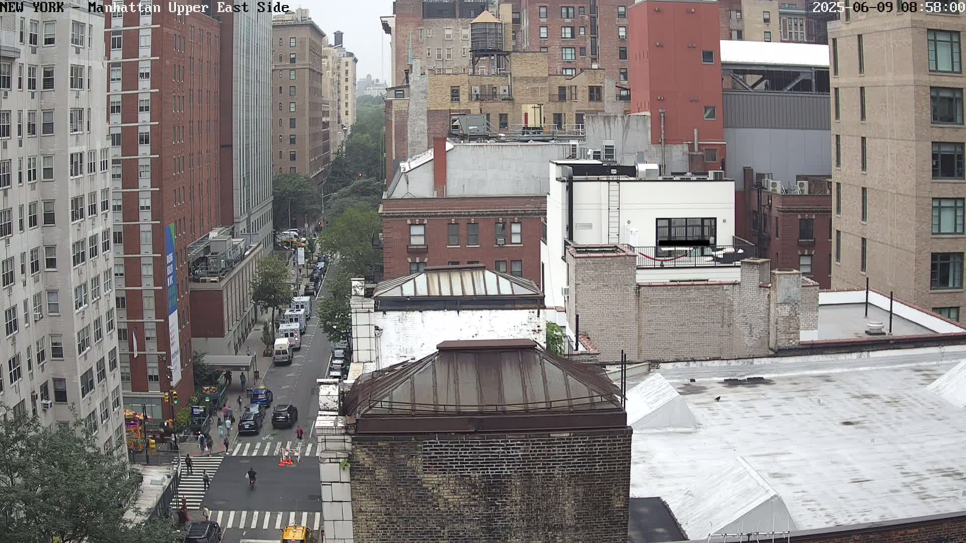 An overcast day reveals a high-angle view of a city street scene, showing multi-story brick buildings and vehicles on a street below.