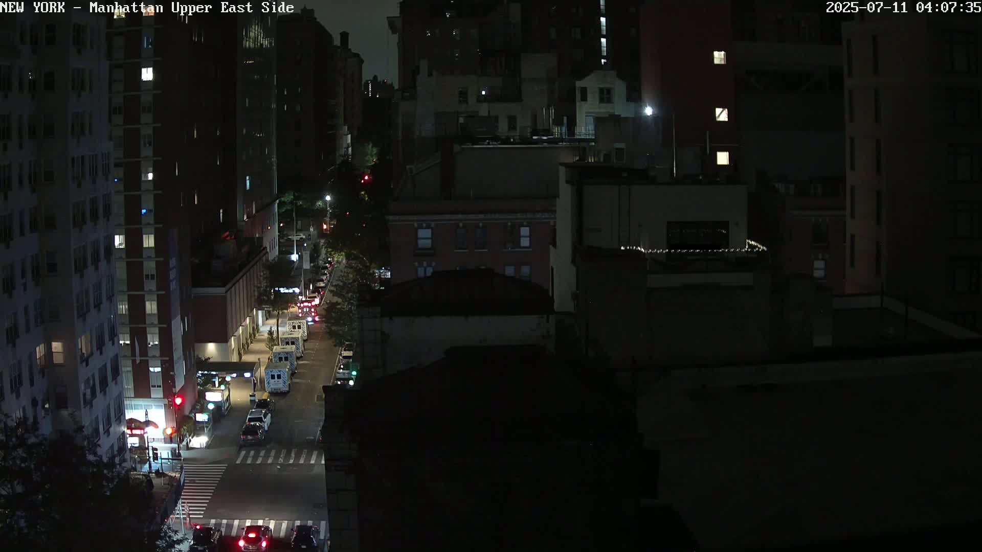 A nighttime, high-angle view of a city street with several cars and buildings.