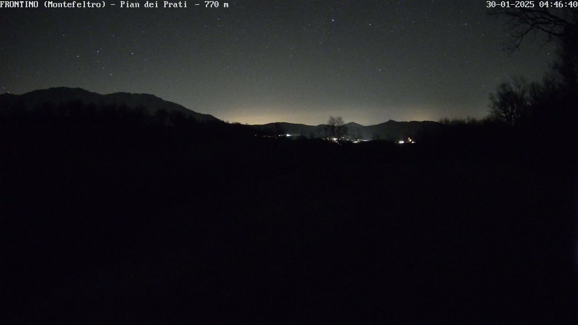 A nighttime view of dark, silhouetted mountains under a starry sky.
