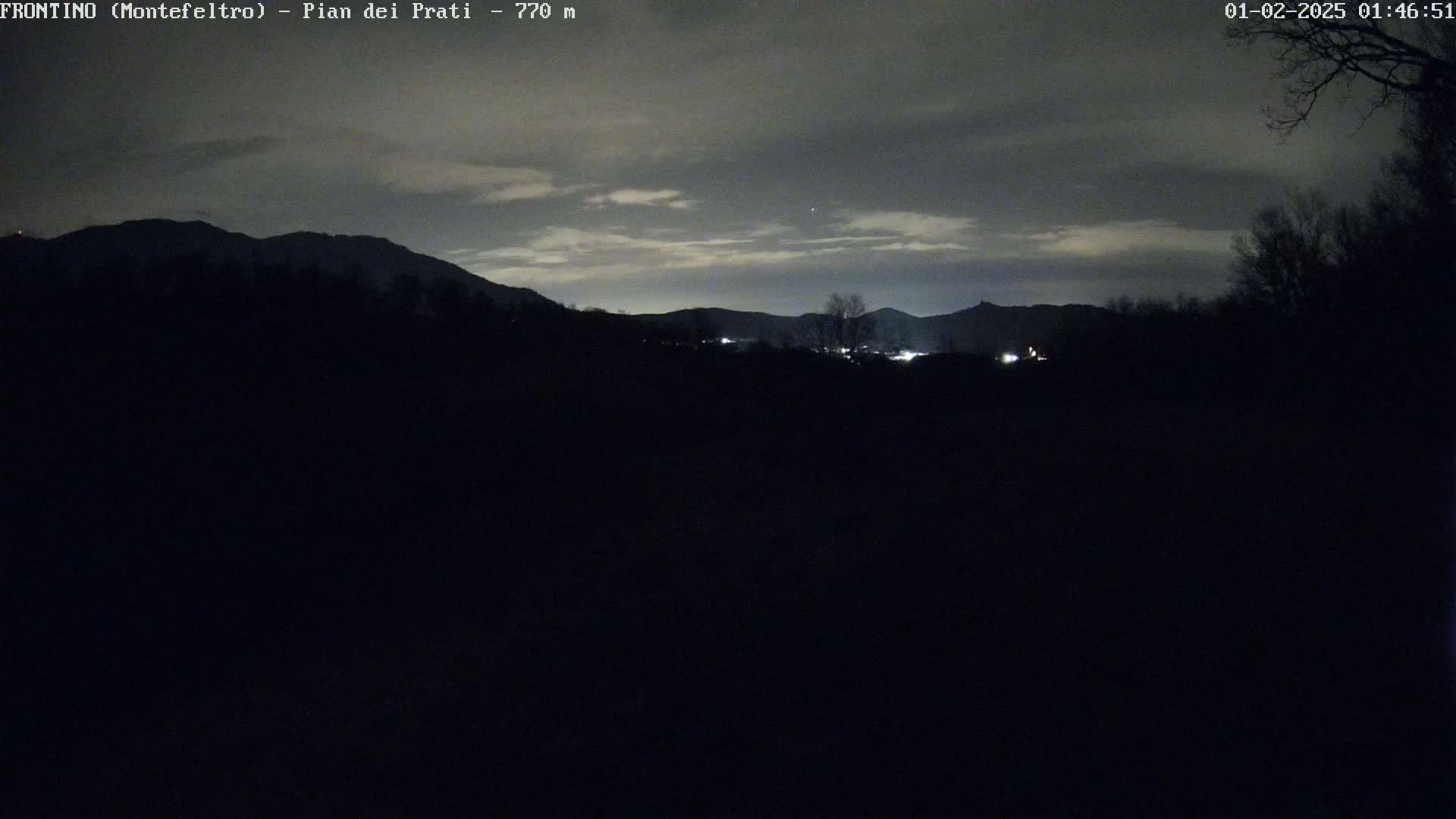 A nighttime view of dimly lit mountains under a cloudy sky.
