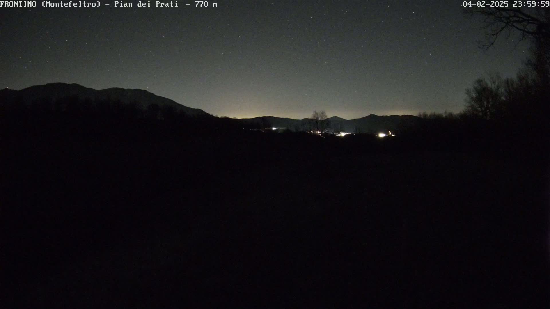A dark, nighttime landscape shows a distant mountain range under a clear, starry sky.