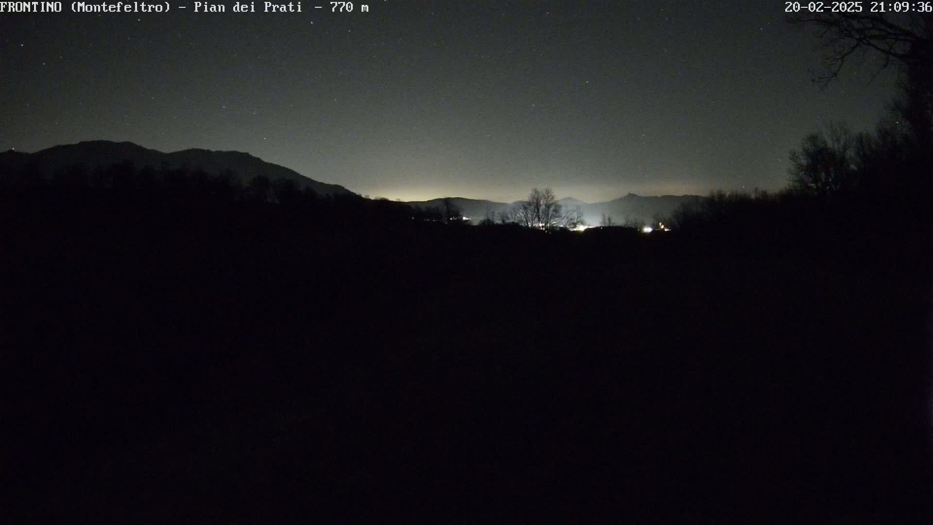 A nighttime view of dimly lit mountains under a starry sky.