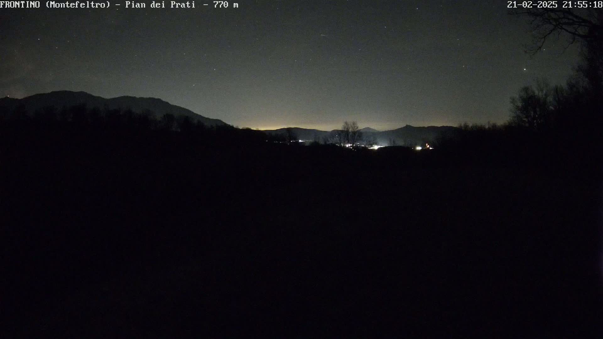 A nighttime long shot shows a dark, silhouetted landscape of mountains and trees under a starry sky.