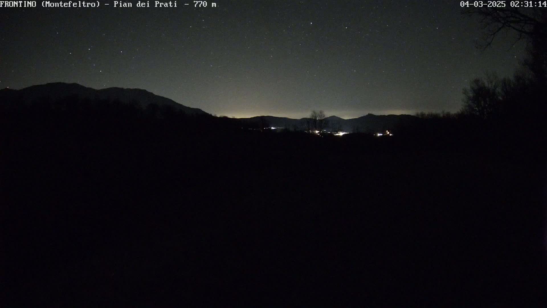 A nighttime long shot shows a dark, mountainous landscape under a clear, starlit sky.