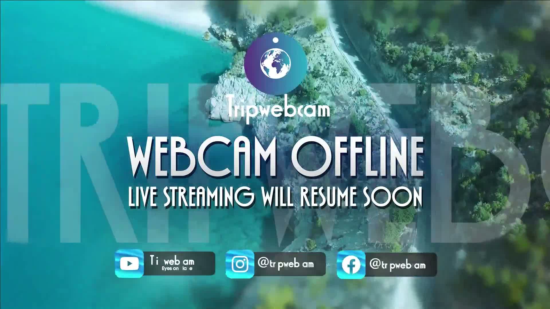 An aerial view of a rocky coastline meeting turquoise water, overlaid with a message indicating that the webcam is offline.