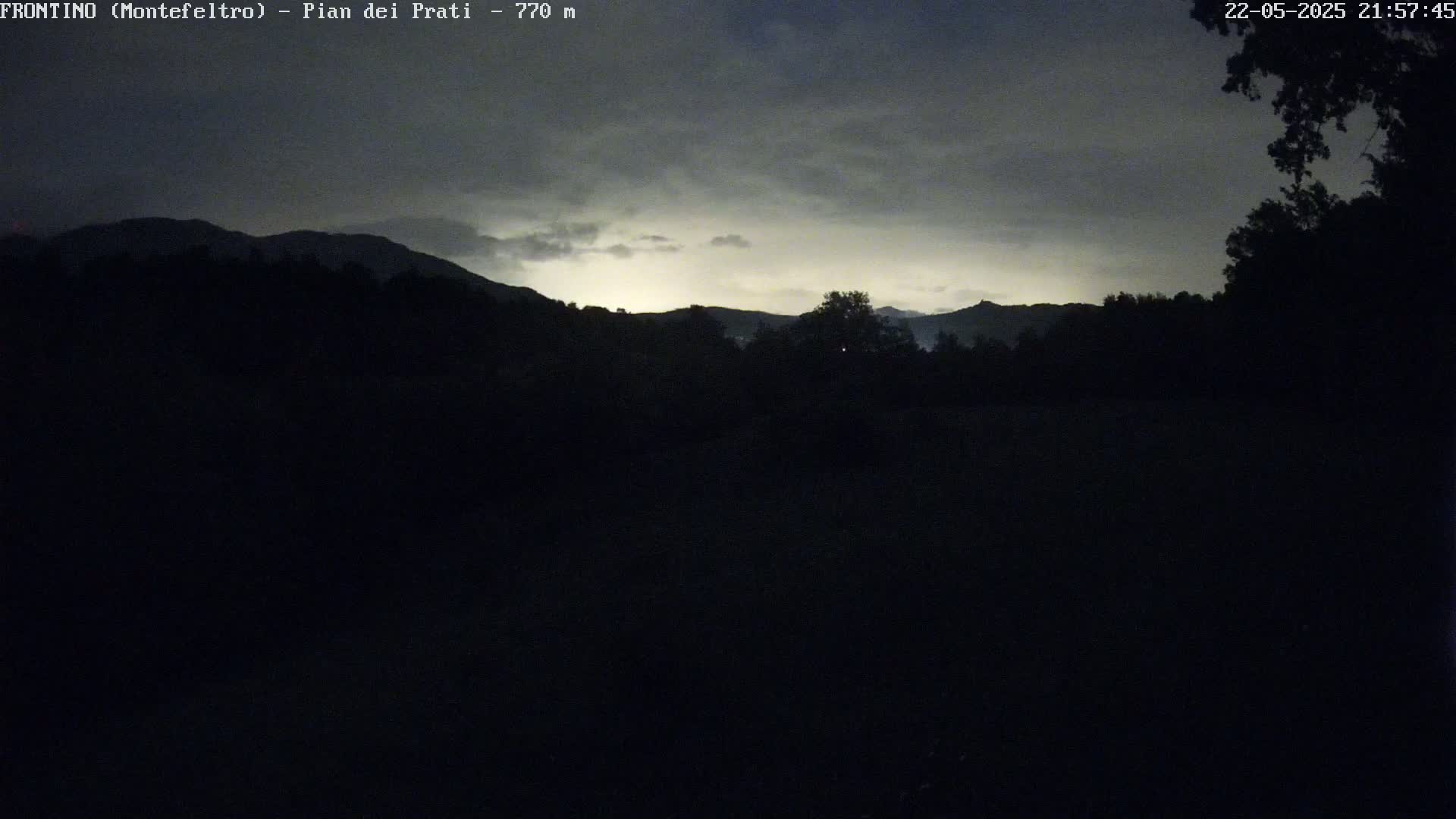Silhouetted mountains are visible under a cloudy, twilight sky.