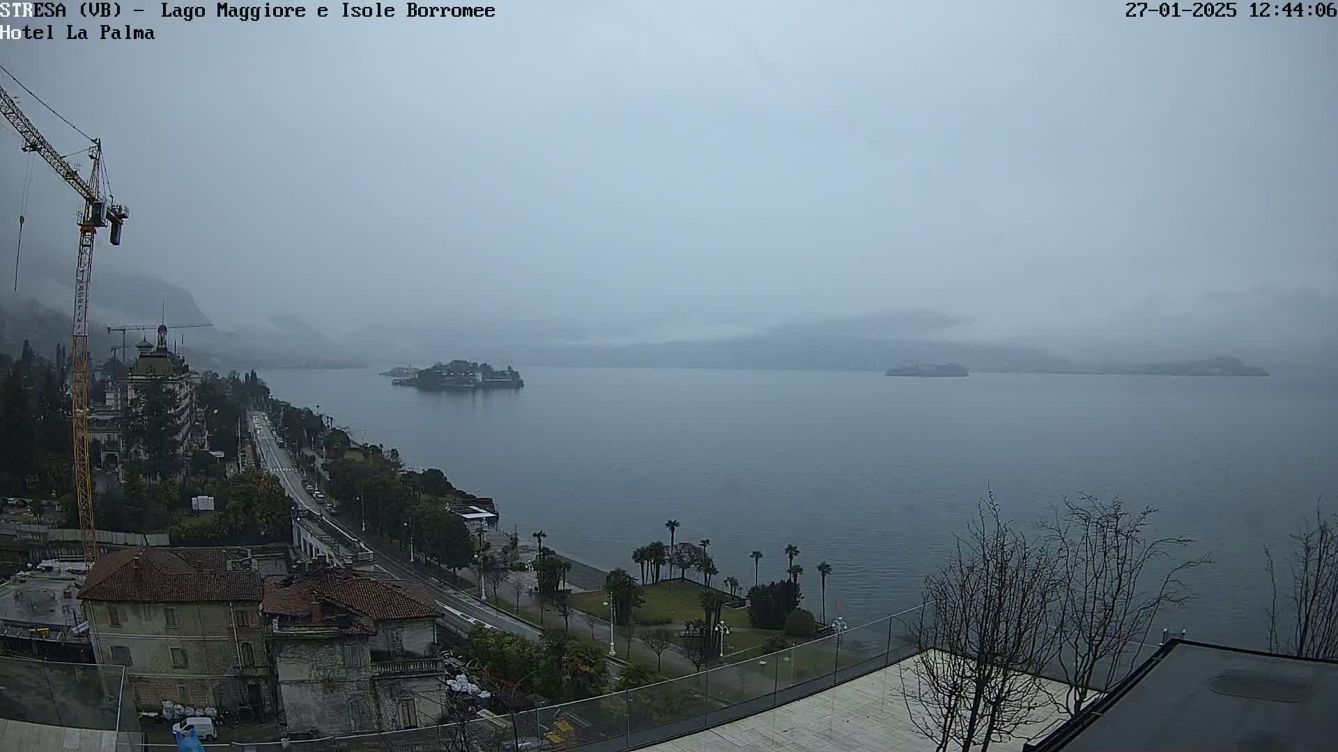 A foggy view overlooking a lake, with a town and construction crane visible in the foreground.