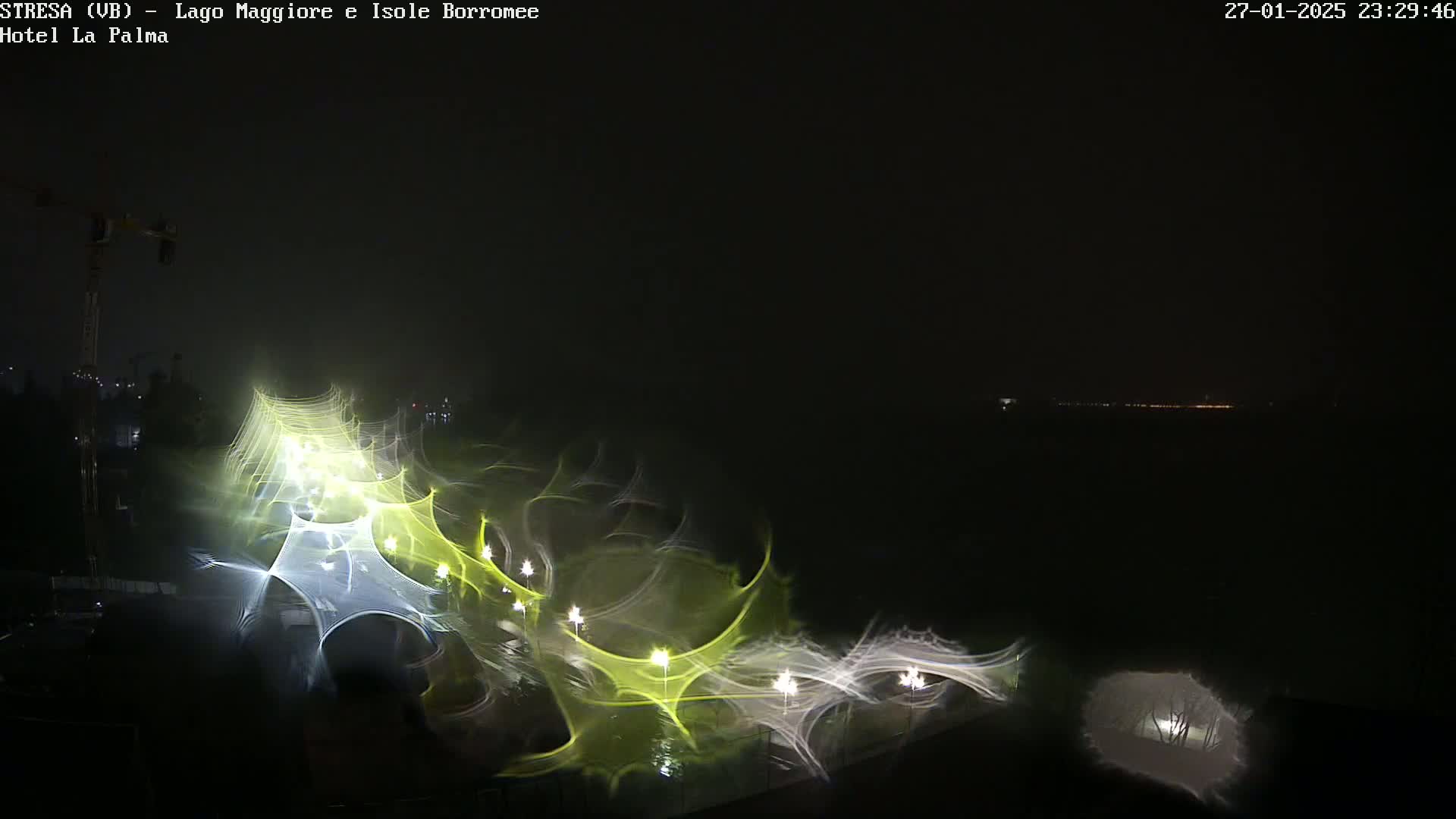 A nighttime long-exposure shot shows blurred lights and structures, possibly along a waterfront, under a dark, possibly foggy sky.