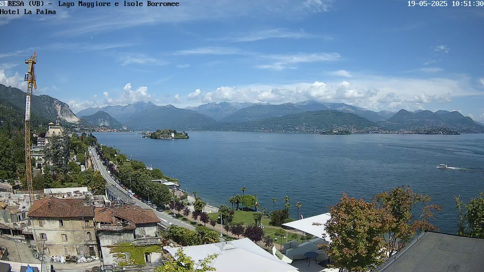 A sunny day overlooking a large lake with mountains in the background, a town along the shore, and a small island visible in the distance.