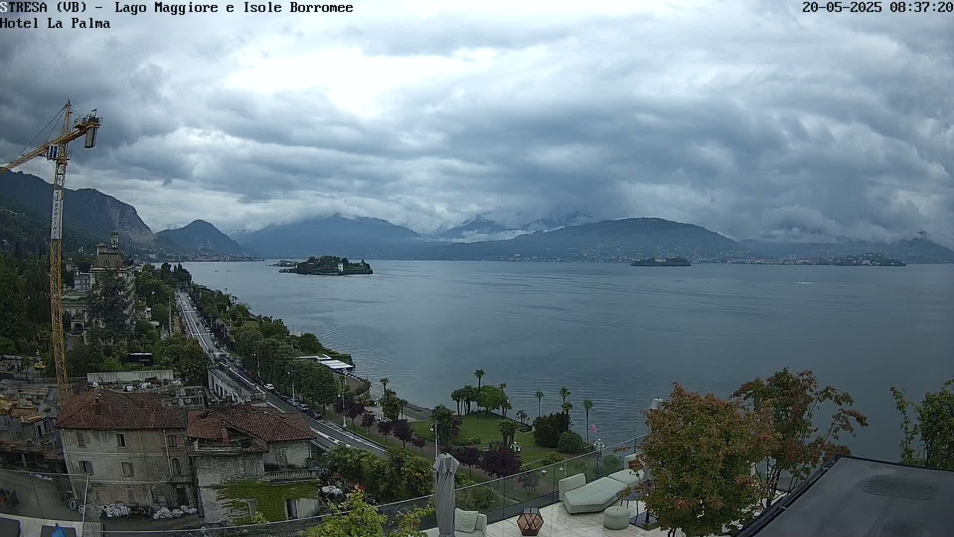 A view of a lake with mountains in the background on an overcast day, seen from a high vantage point overlooking buildings and a road.
