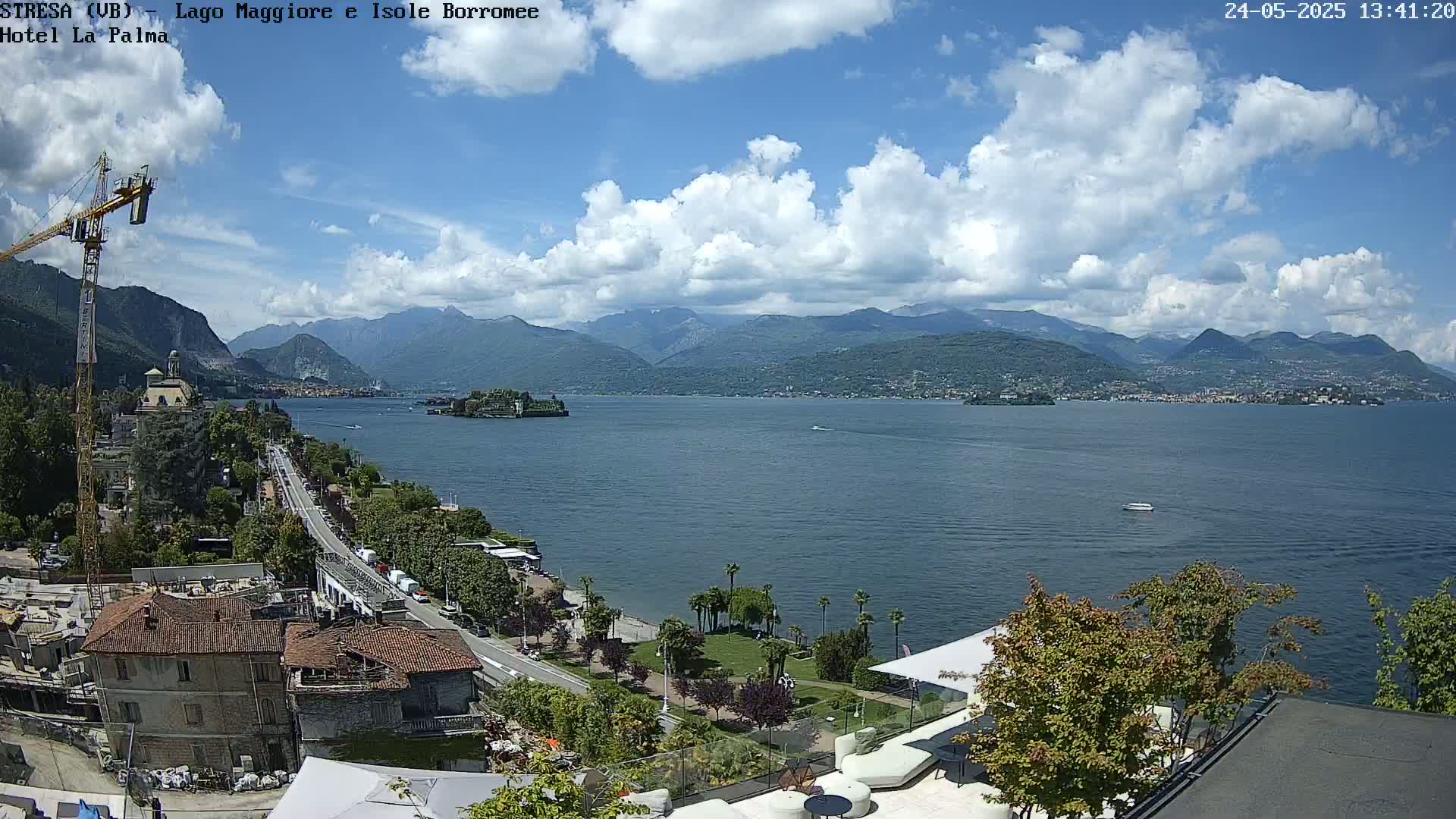 A partly cloudy day overlooking a large lake, with mountains in the background and a town visible along the lakeshore.