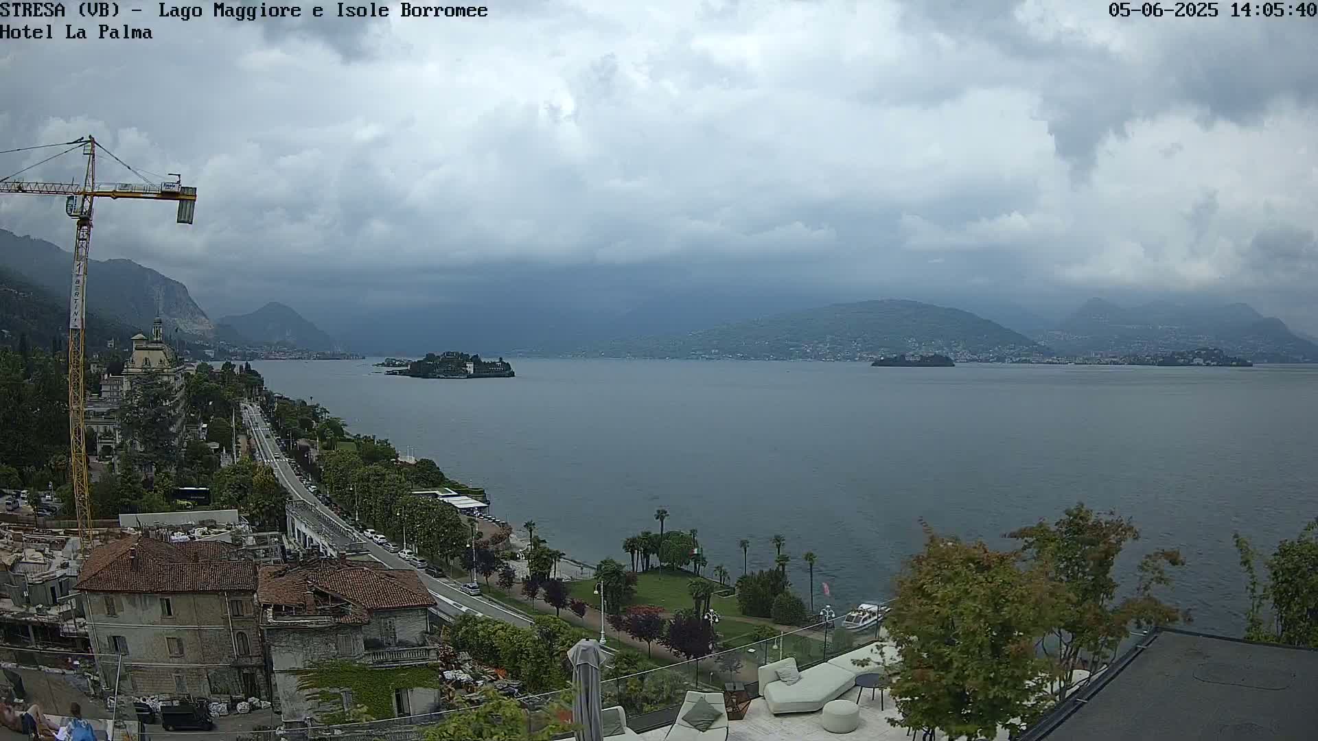 A lake view on an overcast day shows a town nestled along the shoreline, a construction crane, and small islands in the distance.