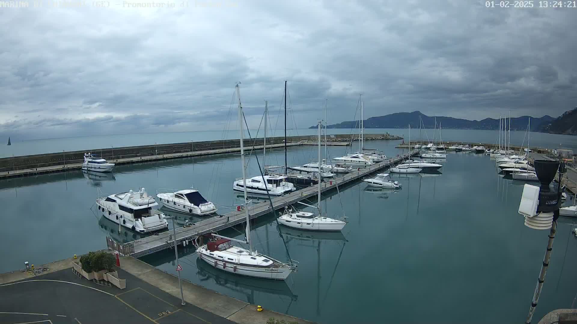 A marina filled with sailboats and motorboats is shown under a cloudy sky.