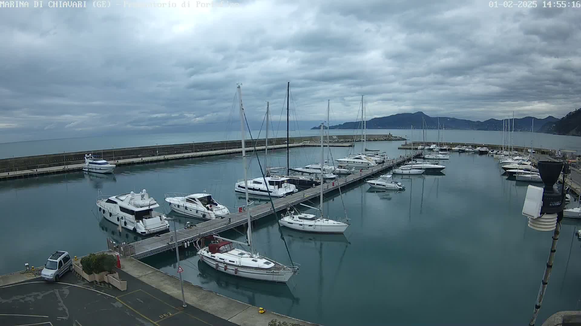 A marina filled with sailboats and motorboats is seen under a cloudy sky.