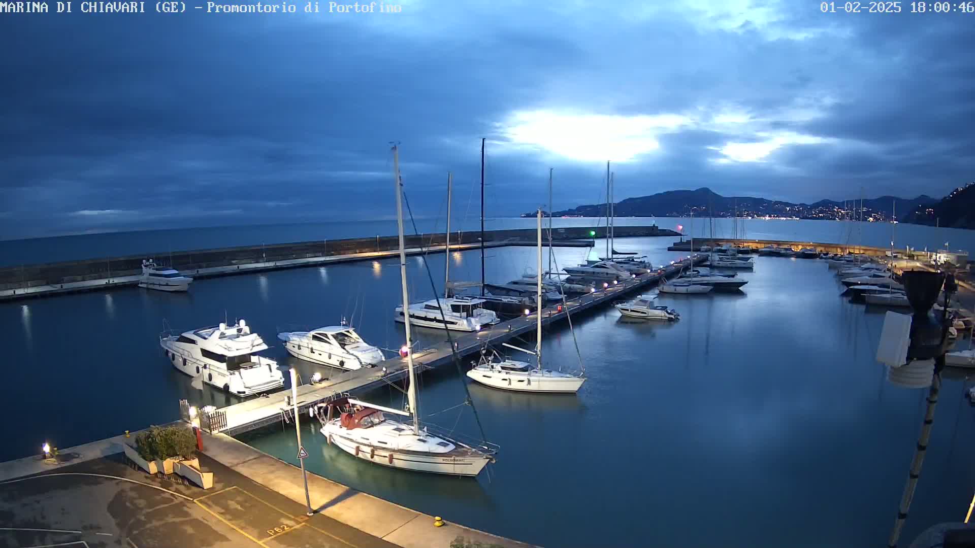 A marina filled with yachts and sailboats at dusk under a partly cloudy sky.