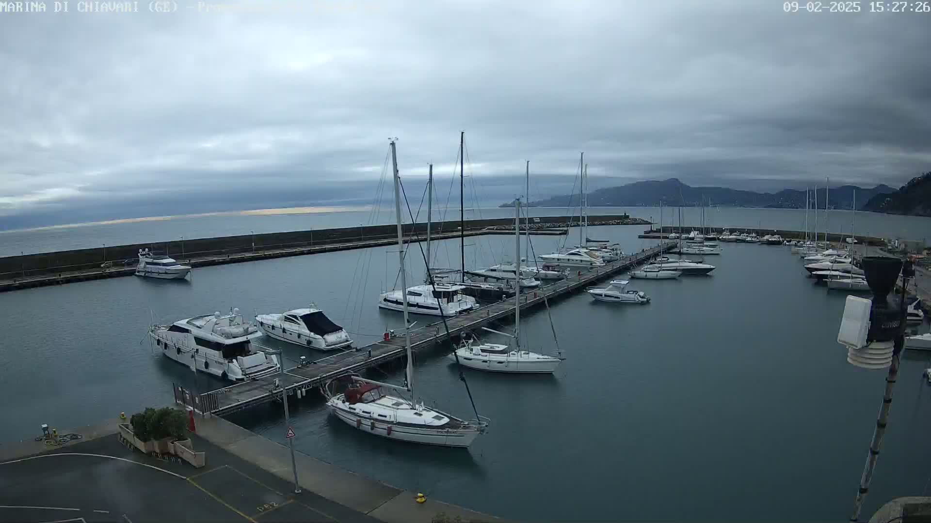 A marina filled with numerous sailboats and motorboats under a cloudy sky.