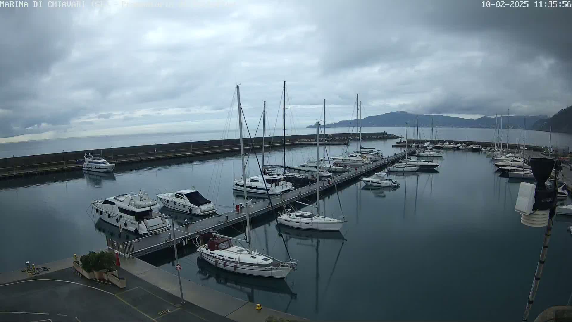 A marina filled with sailboats and motorboats is shown under a cloudy sky.