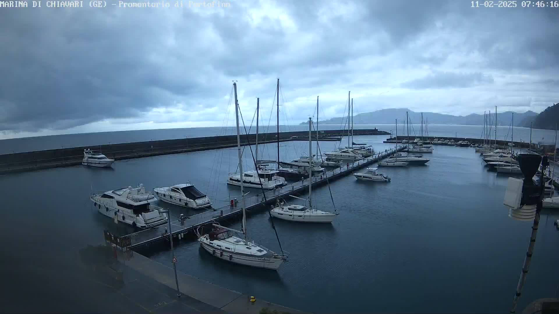 A marina filled with sailboats and motorboats under a cloudy sky.