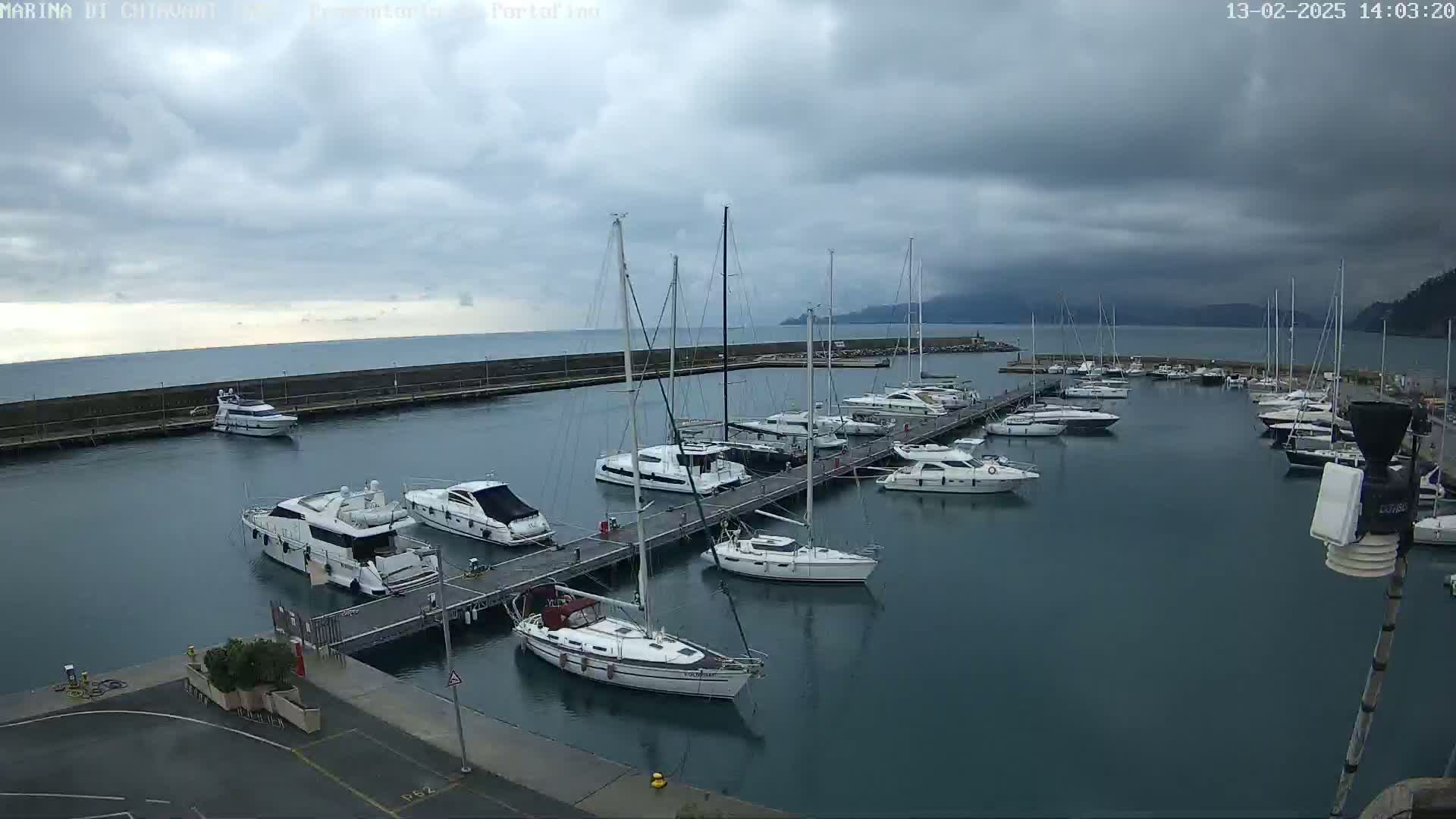 A marina filled with sailboats and motor yachts under a cloudy sky.