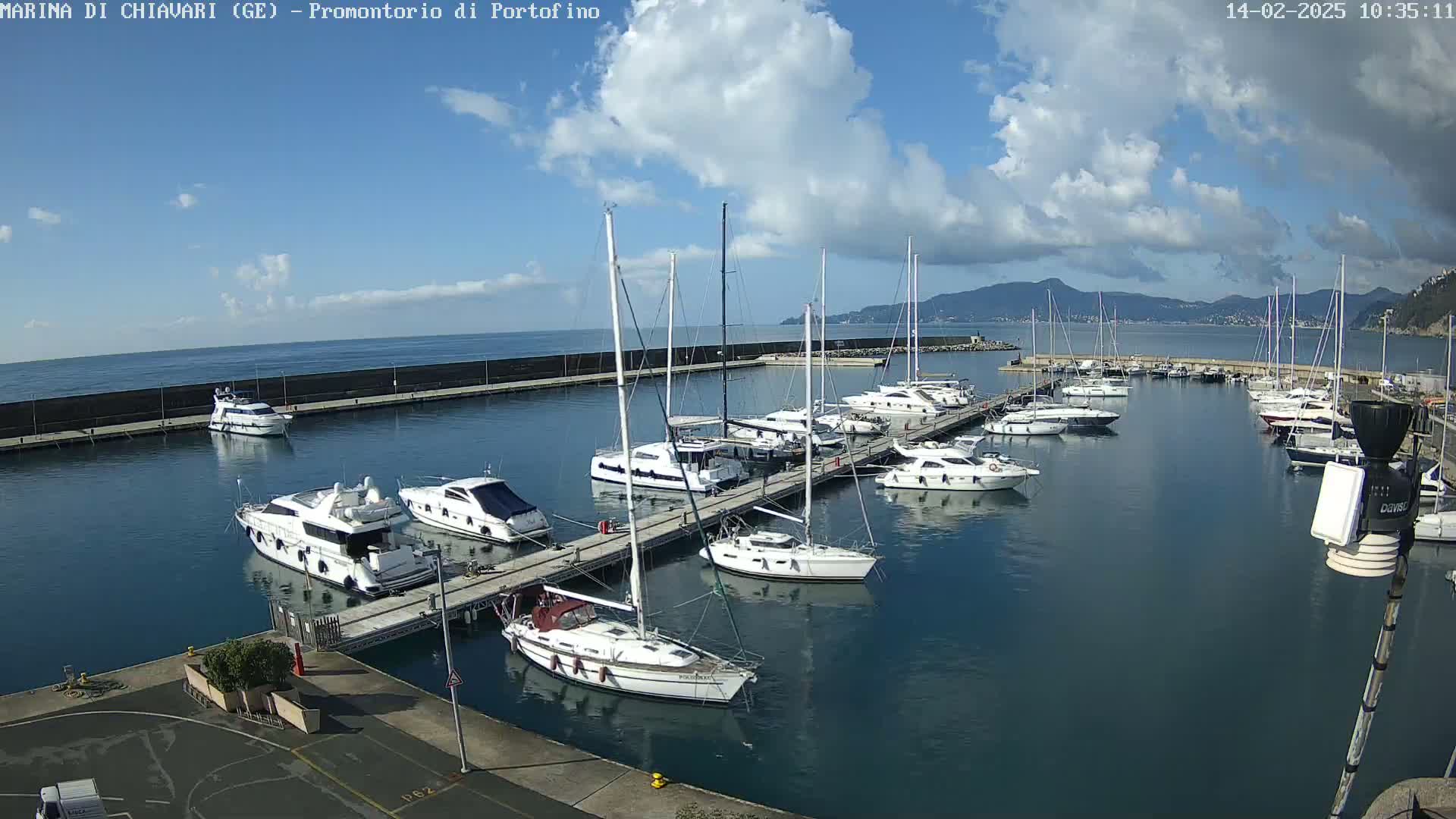 A marina filled with sailboats and motorboats on a partly cloudy day.
