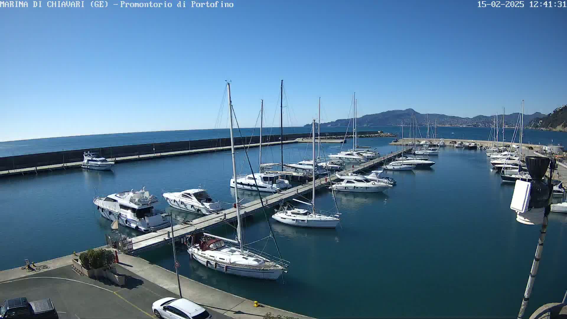 A marina filled with sailboats and motorboats is shown on a clear, sunny day.