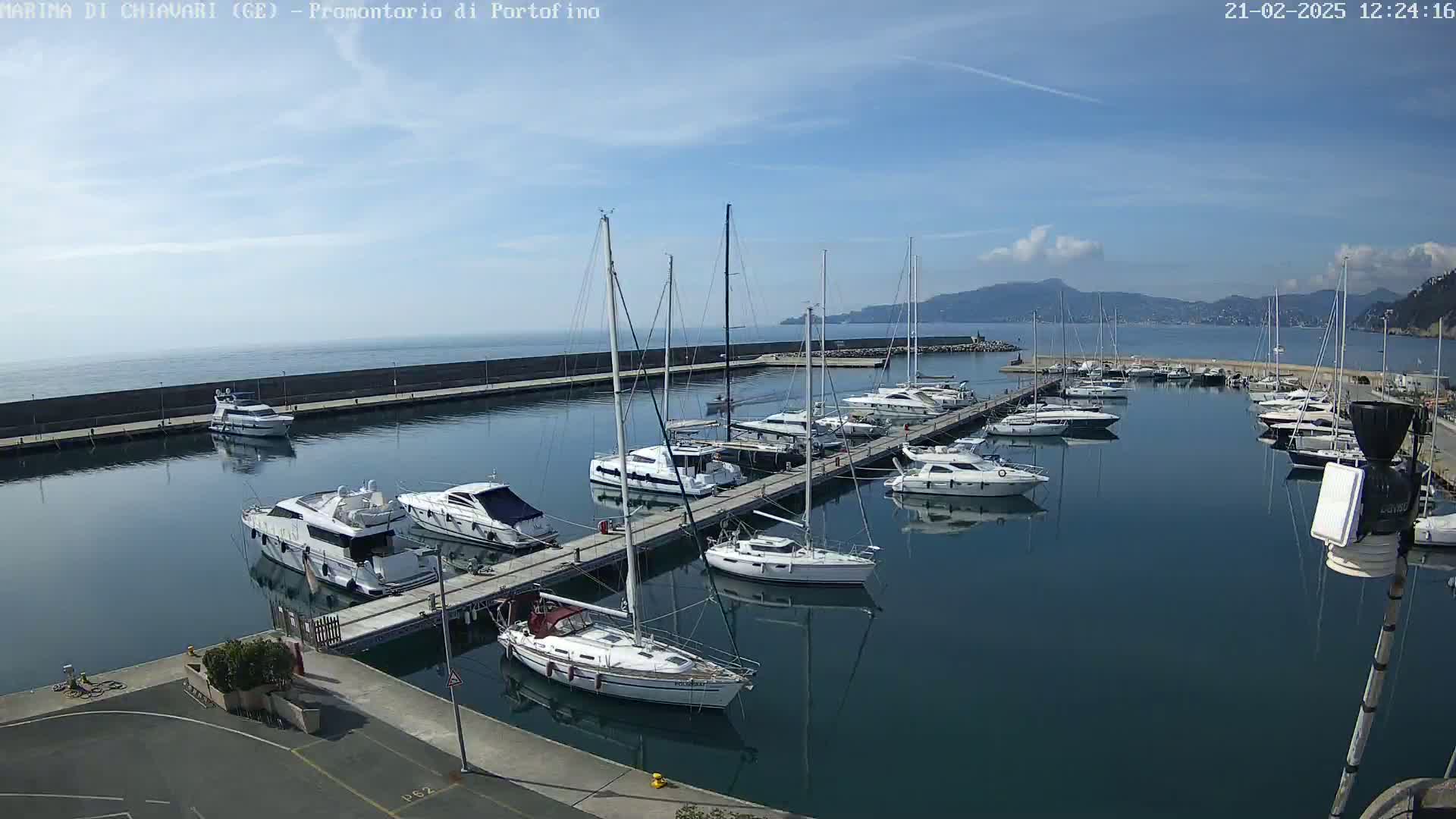 A marina filled with sailboats and motor yachts on a sunny day with a partly cloudy sky and calm water.