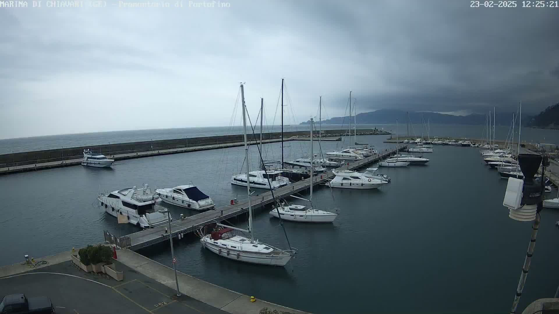 A marina filled with sailboats and motorboats is seen under an overcast sky.