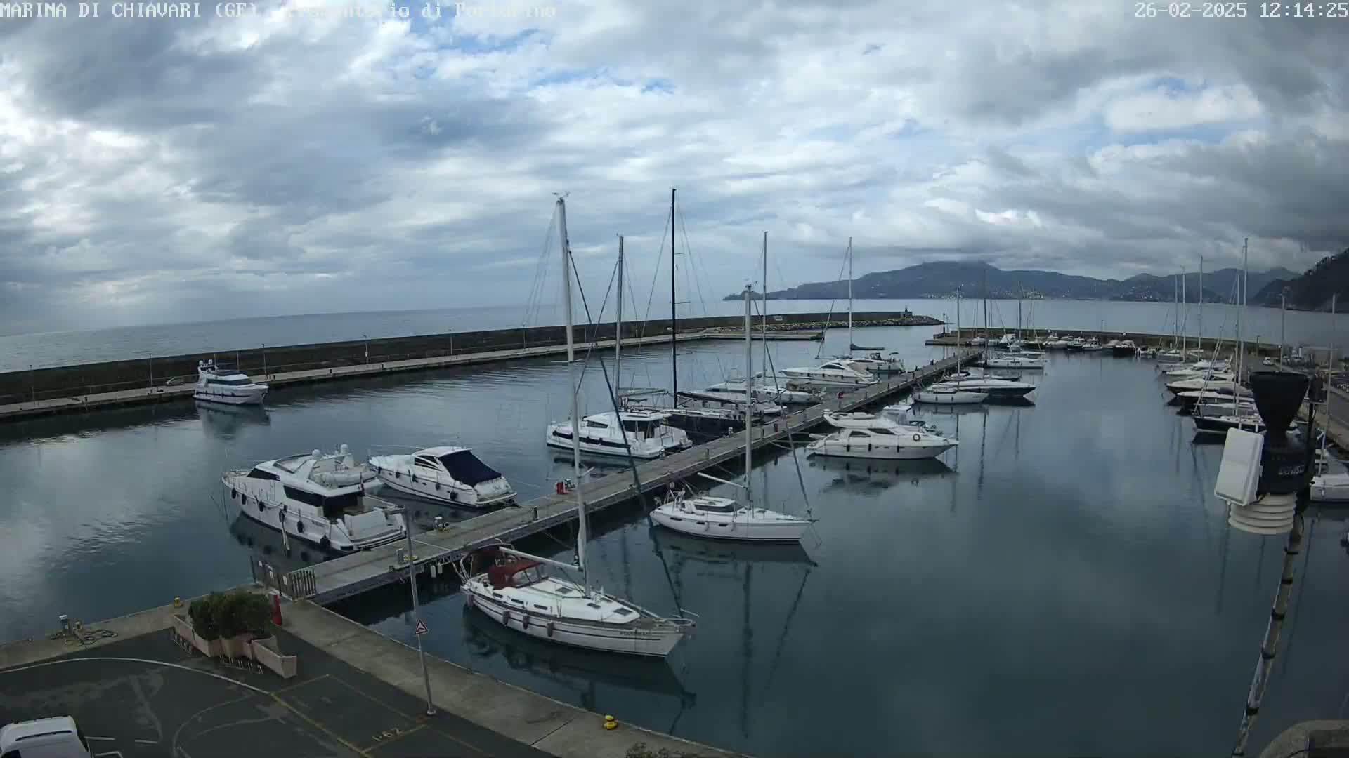 A marina filled with sailboats and motorboats under a partly cloudy sky.
