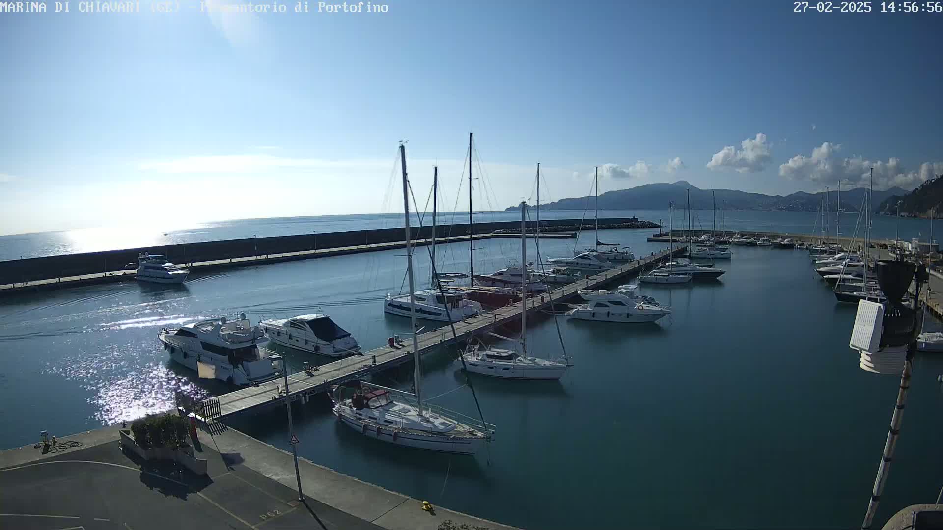 A marina filled with sailboats and motorboats on a partly sunny day with a few clouds.