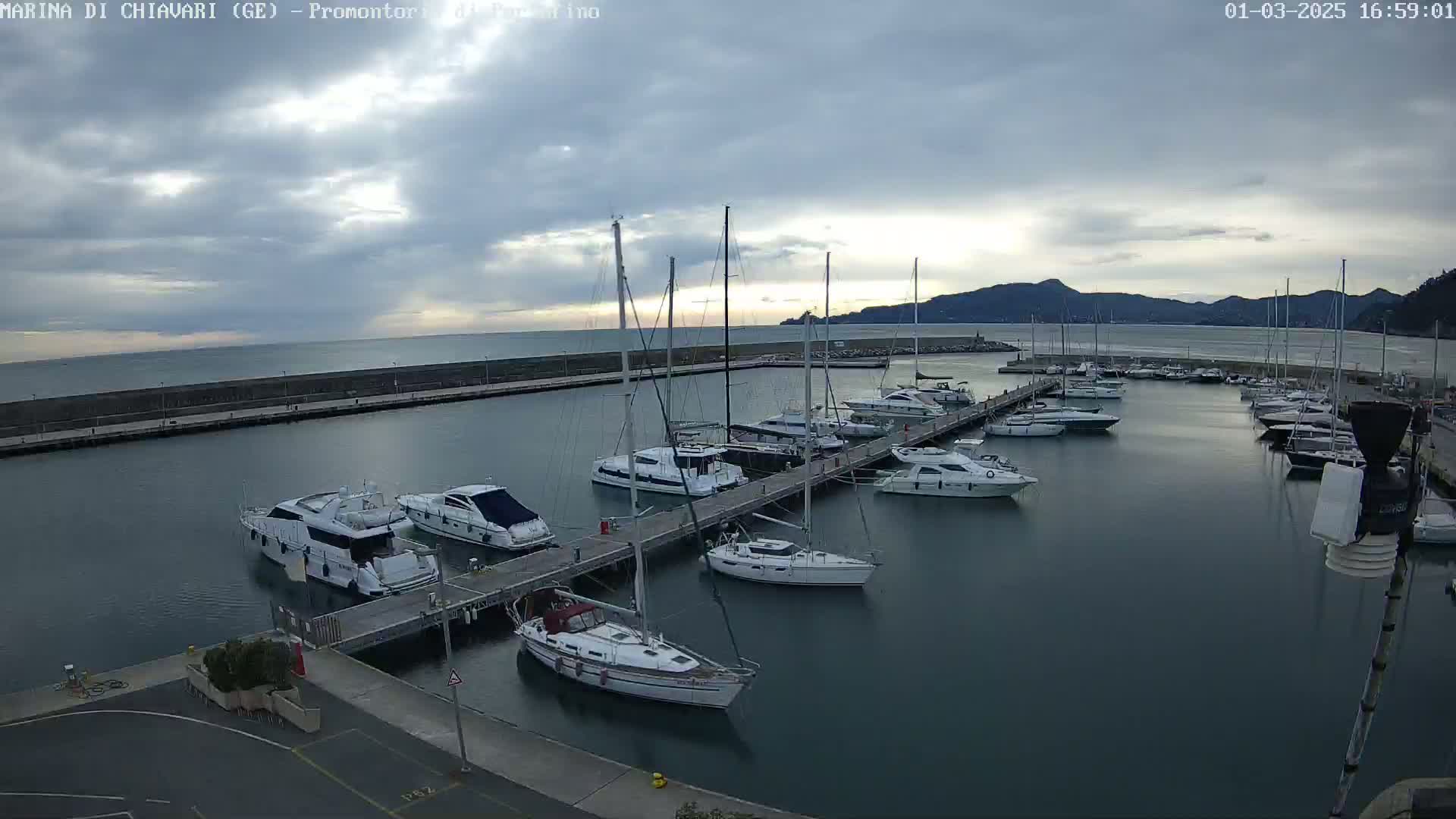 A marina filled with sailboats and motorboats under a cloudy sky.