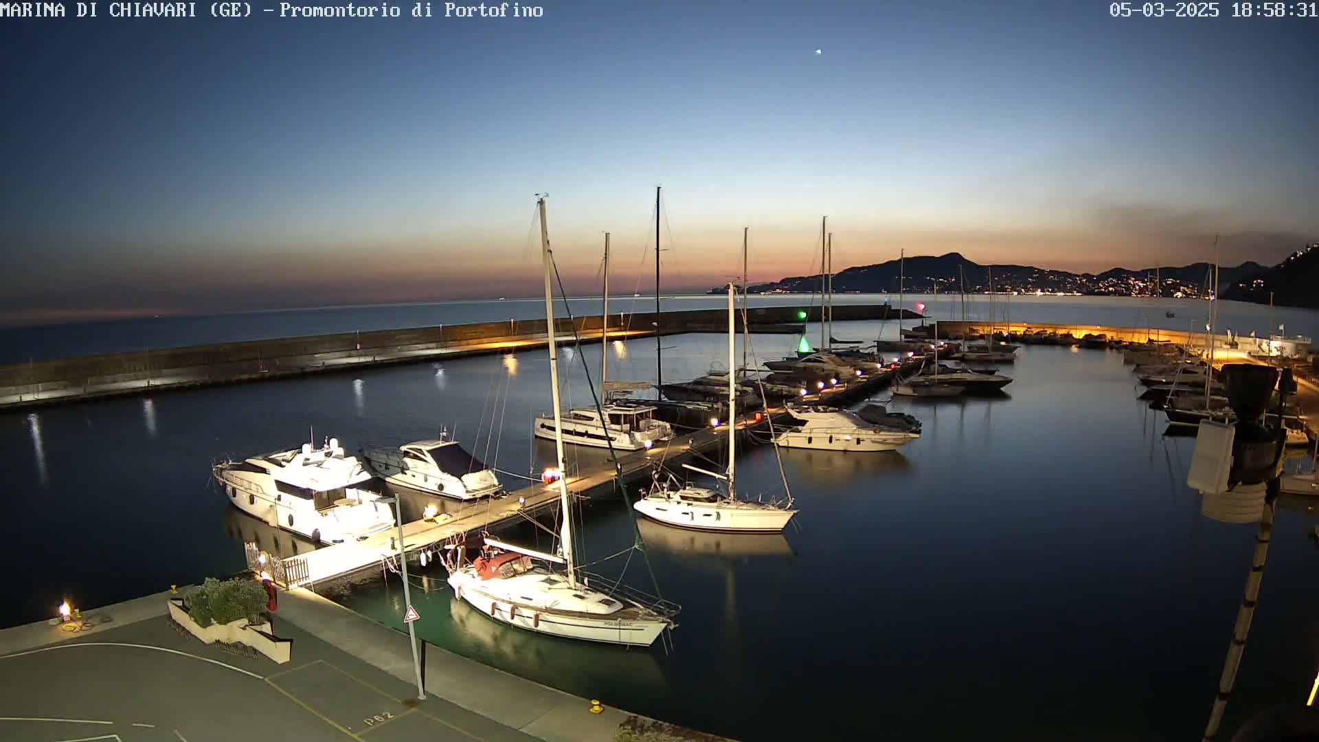 A marina filled with yachts and sailboats at twilight under a clear sky.