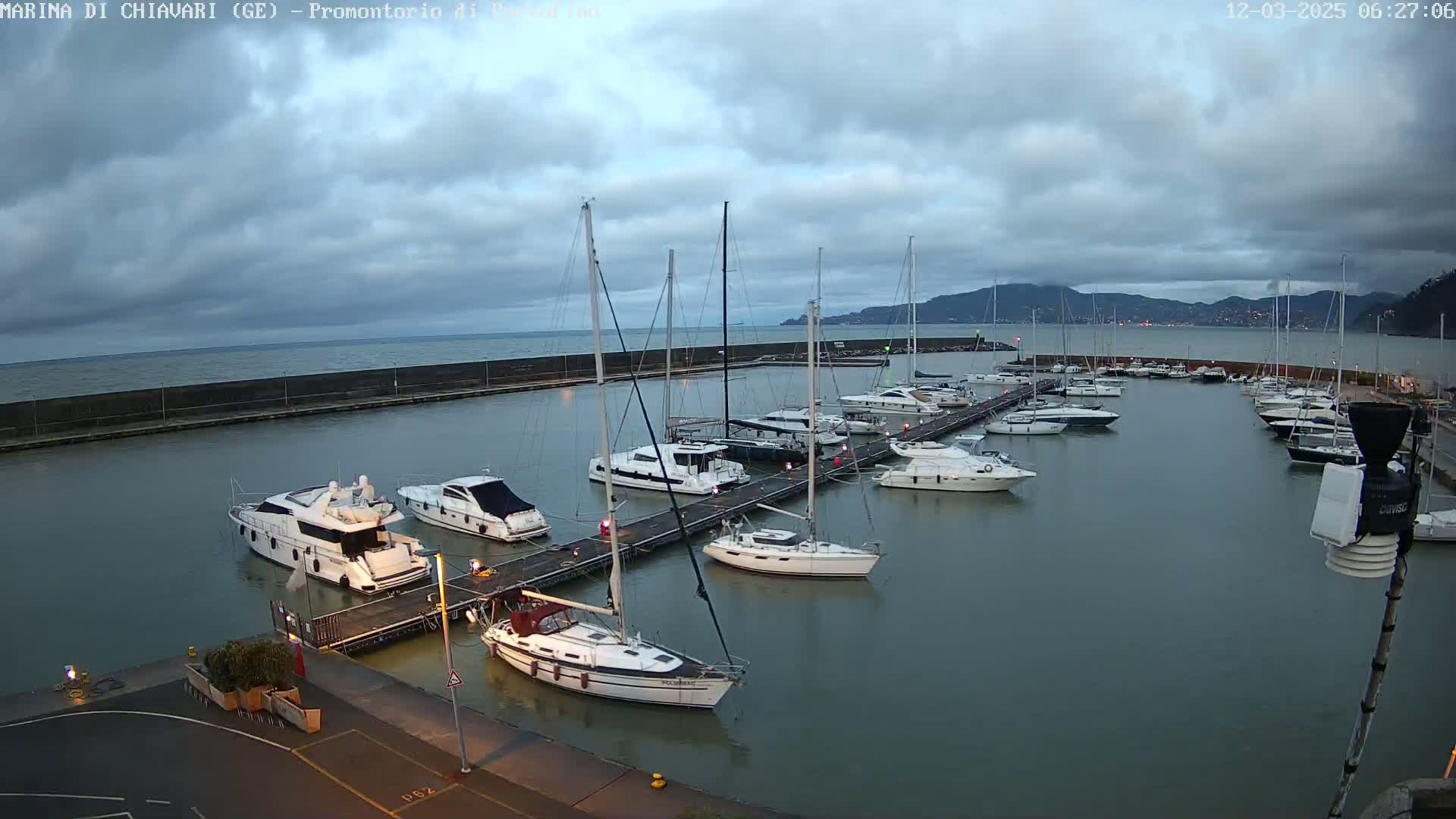 A marina filled with sailboats and motorboats is shown under a cloudy sky.