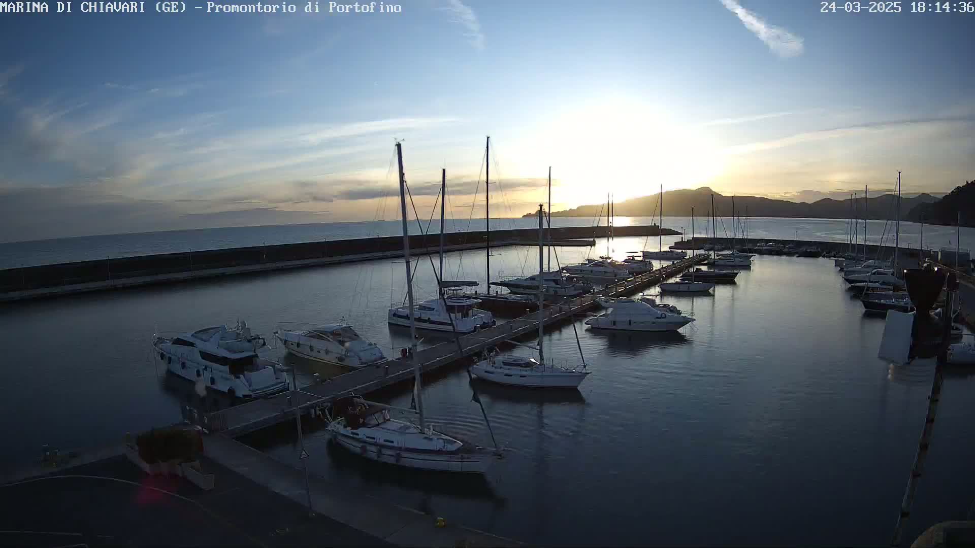 A marina filled with sailboats and yachts at sunset under a mostly clear sky.