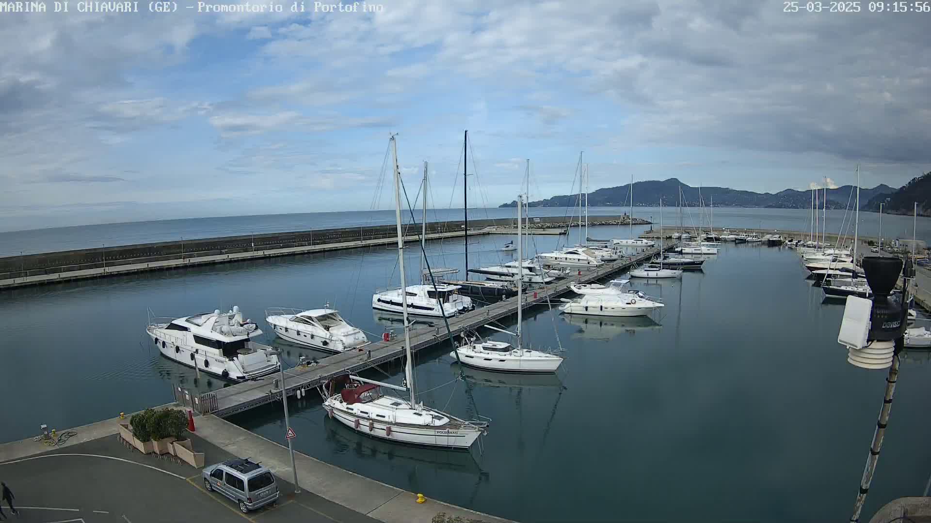 A marina filled with sailboats and motorboats under a partly cloudy sky.