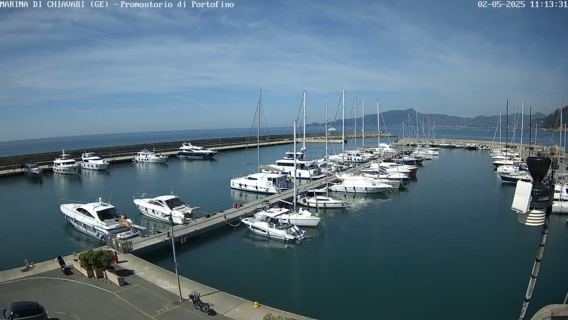 A marina filled with numerous sailboats and motorboats under a mostly sunny sky.