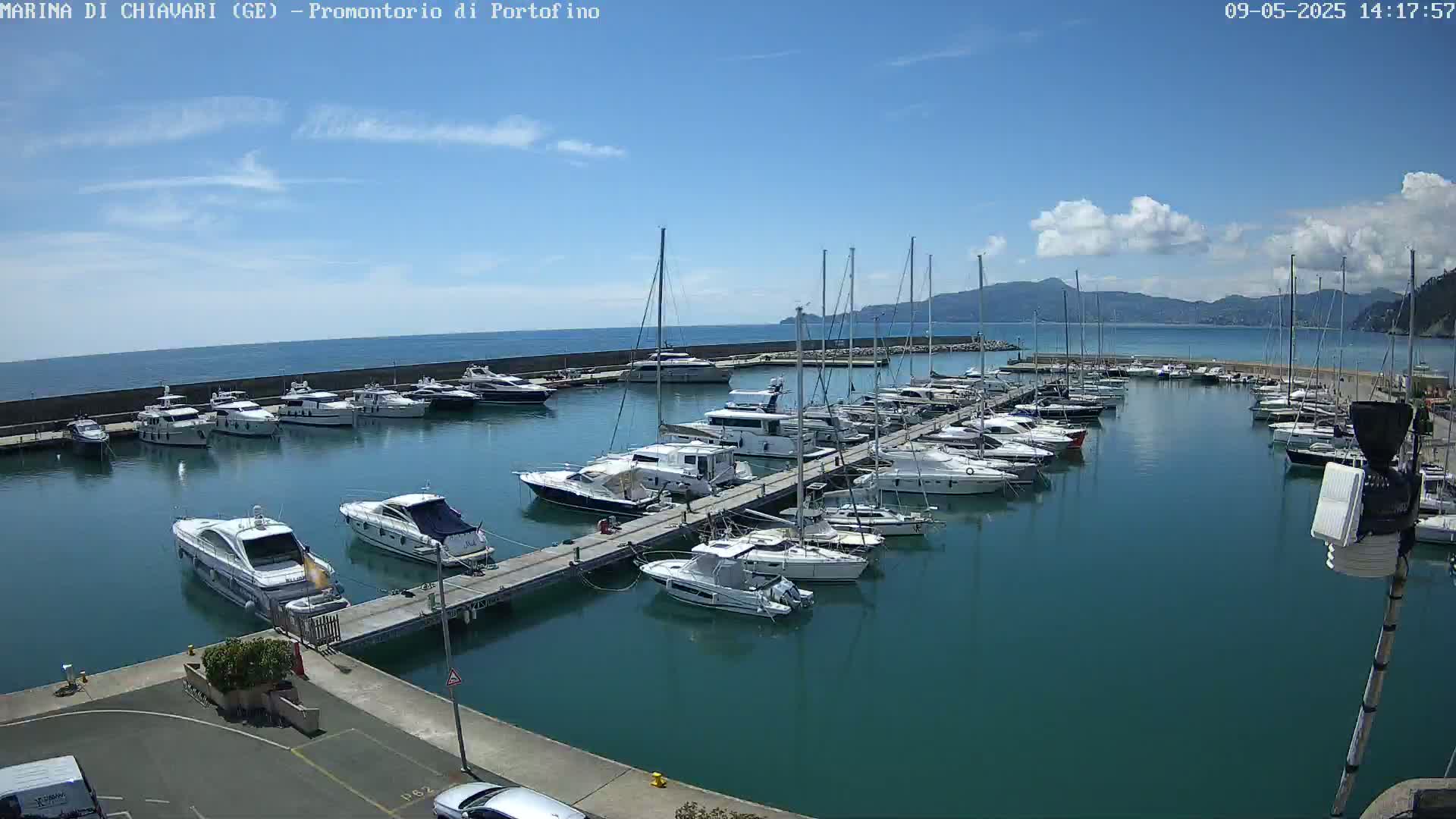 A marina filled with numerous yachts and sailboats under a mostly sunny sky with a few scattered clouds.