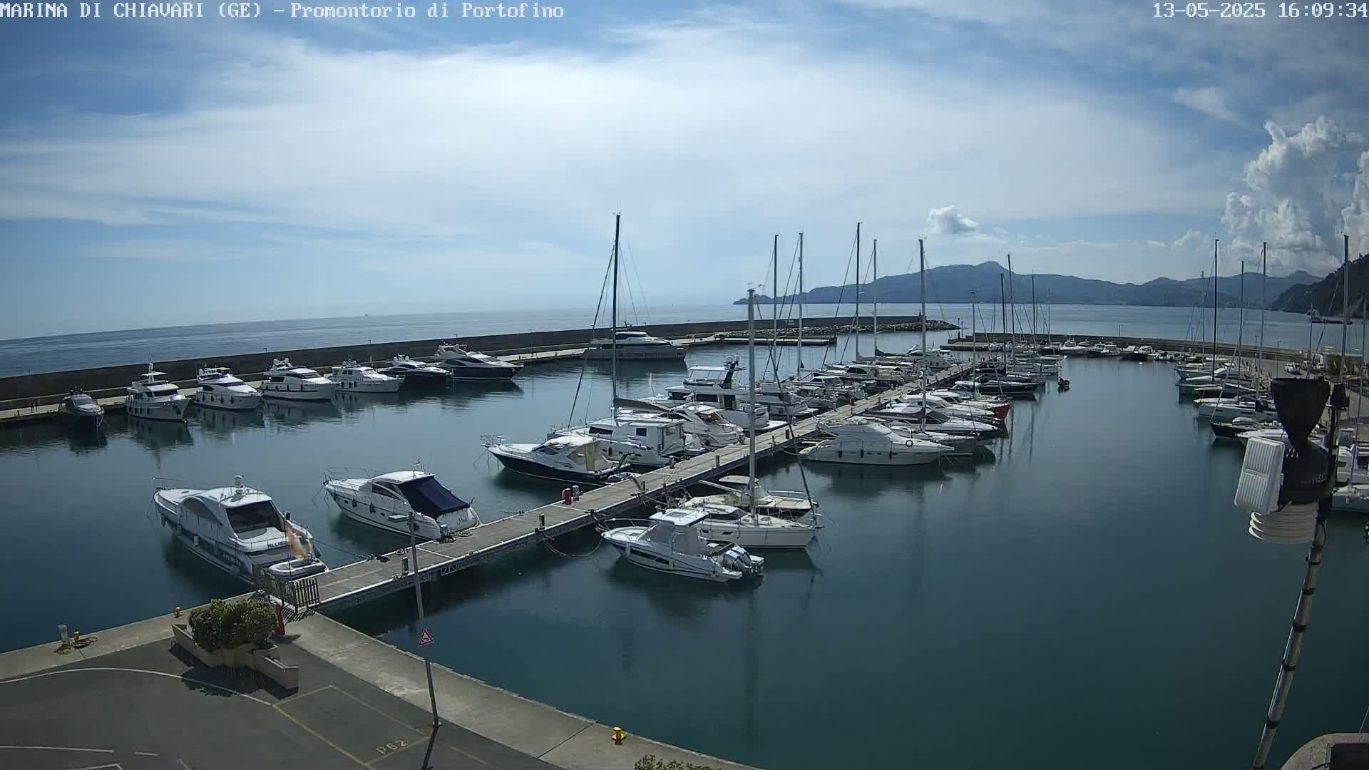 A marina filled with yachts and sailboats on a partly cloudy day.