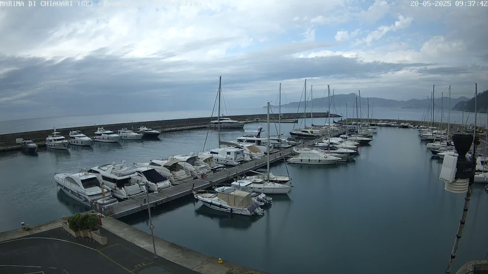 A marina filled with numerous yachts and sailboats under a partly cloudy sky.